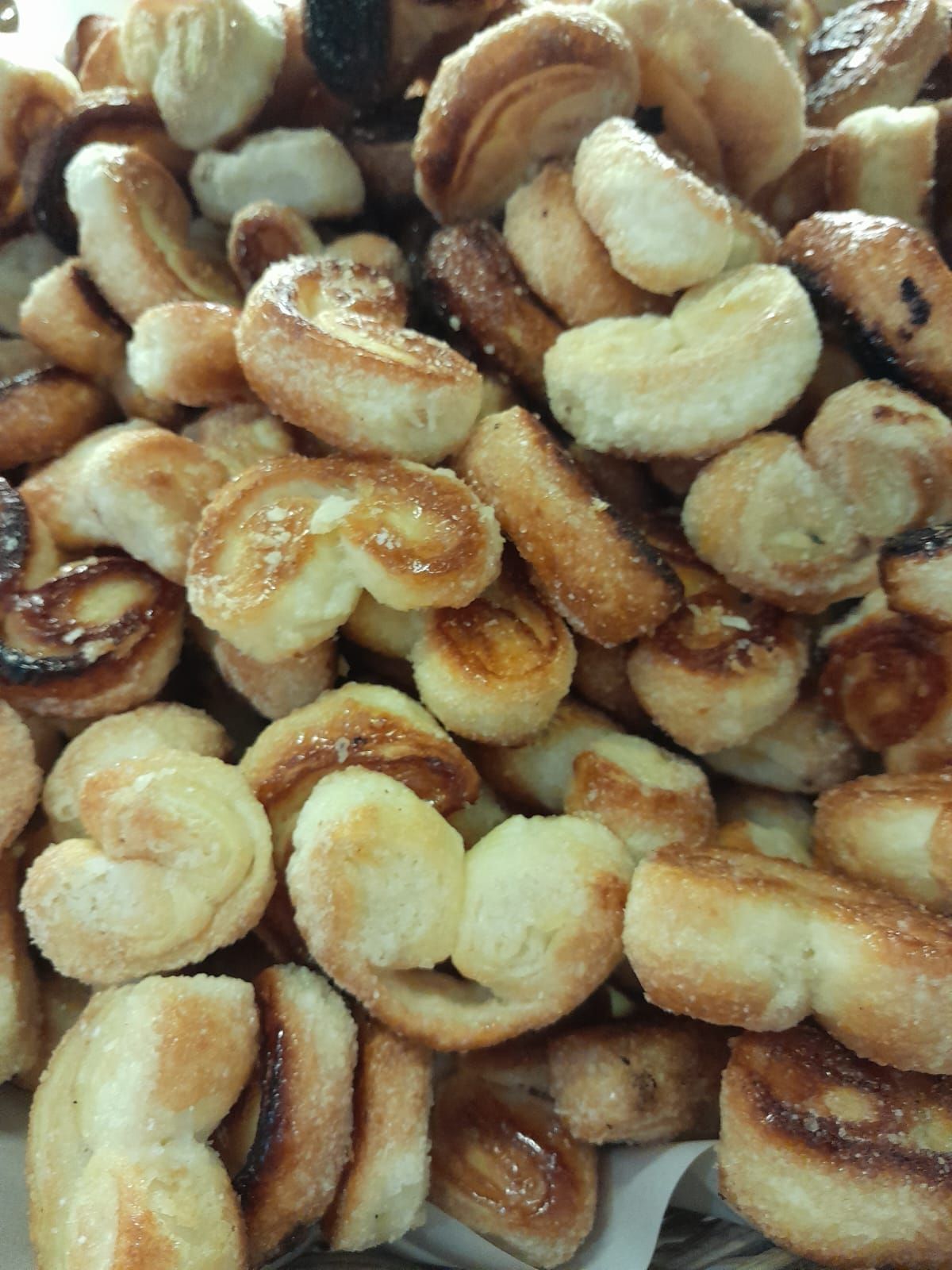 Pila de palmiers dorados y cubiertos de azúcar, un pastel francés con bordes caramelizados.