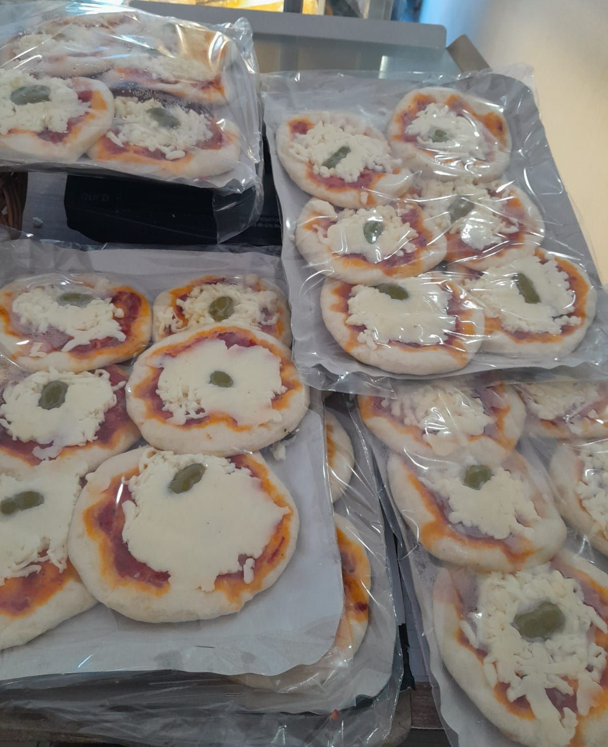 Mini pizzas con salsa, queso y aceitunas presentadas en paquetes.