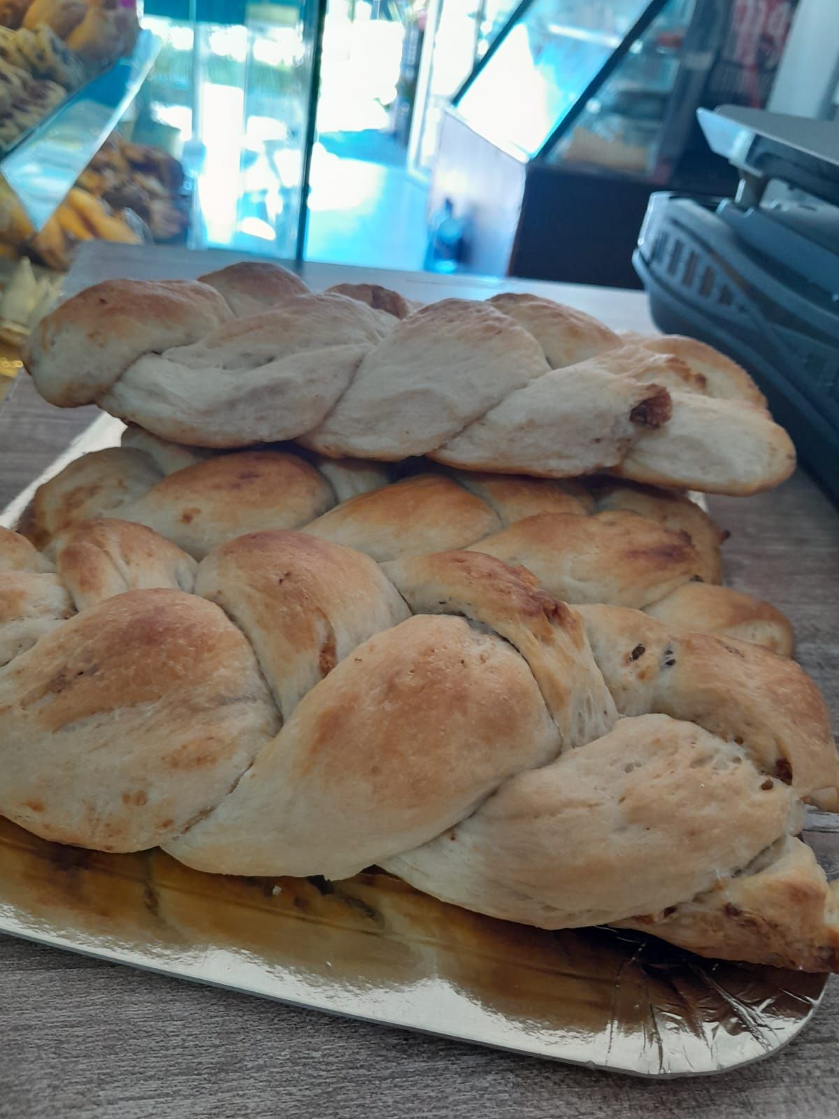 Dos panes trenzados en una bandeja dorada en una panadería.
