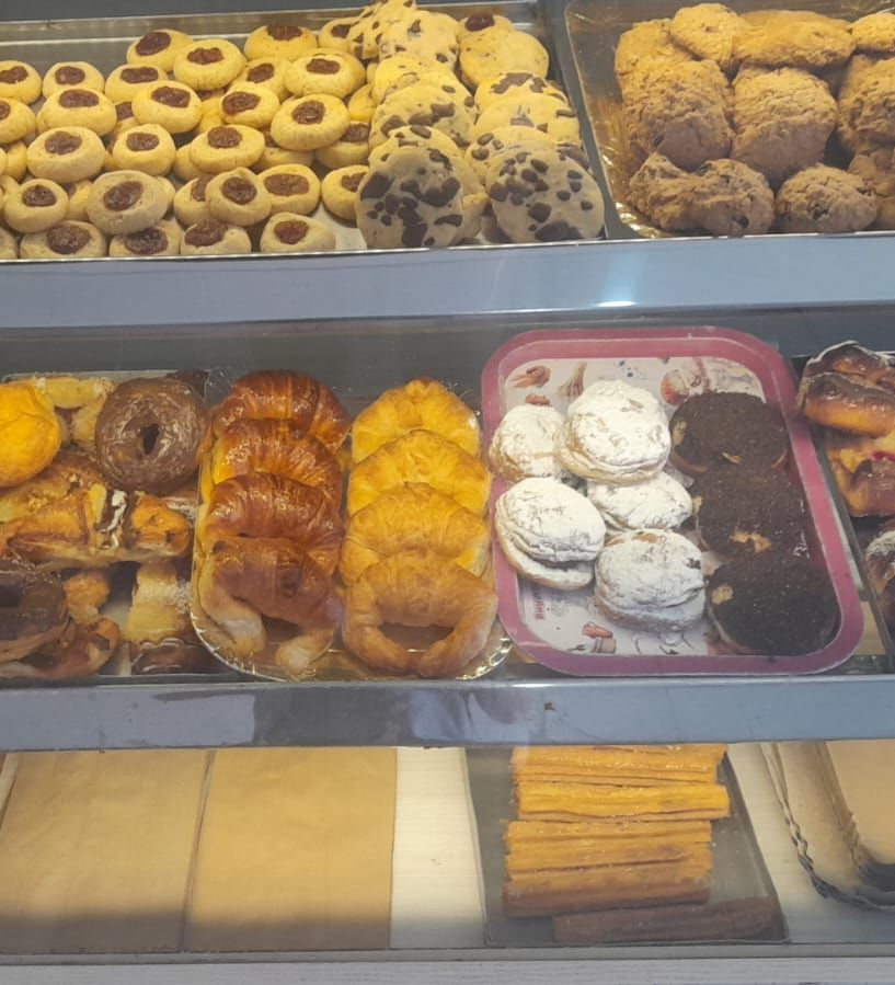 Vitrina de panadería llena de diversos productos horneados: galletas, pasteles y pan.