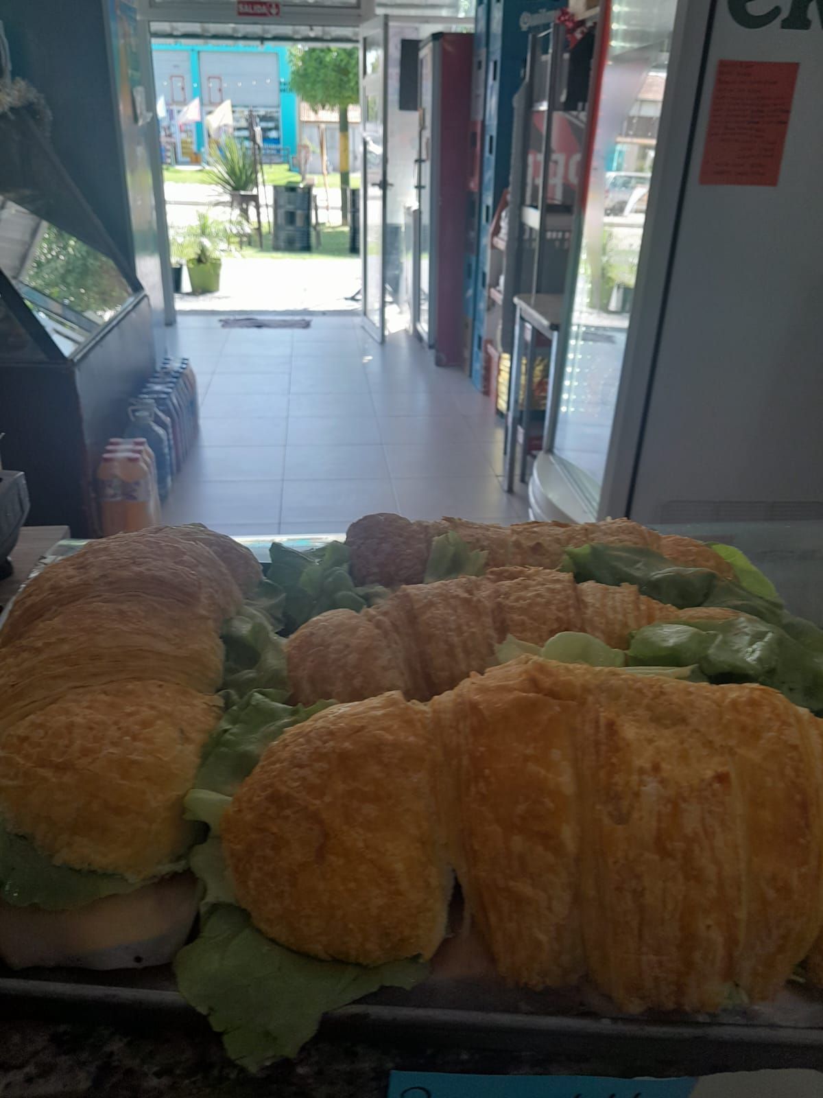 Sándwiches sobre lechuga dentro de una tienda con puerta abierta al exterior.