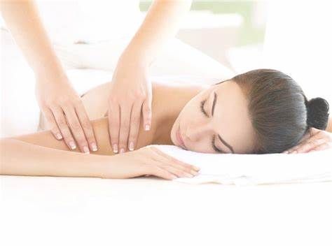 A woman is laying on a bed getting a massage.