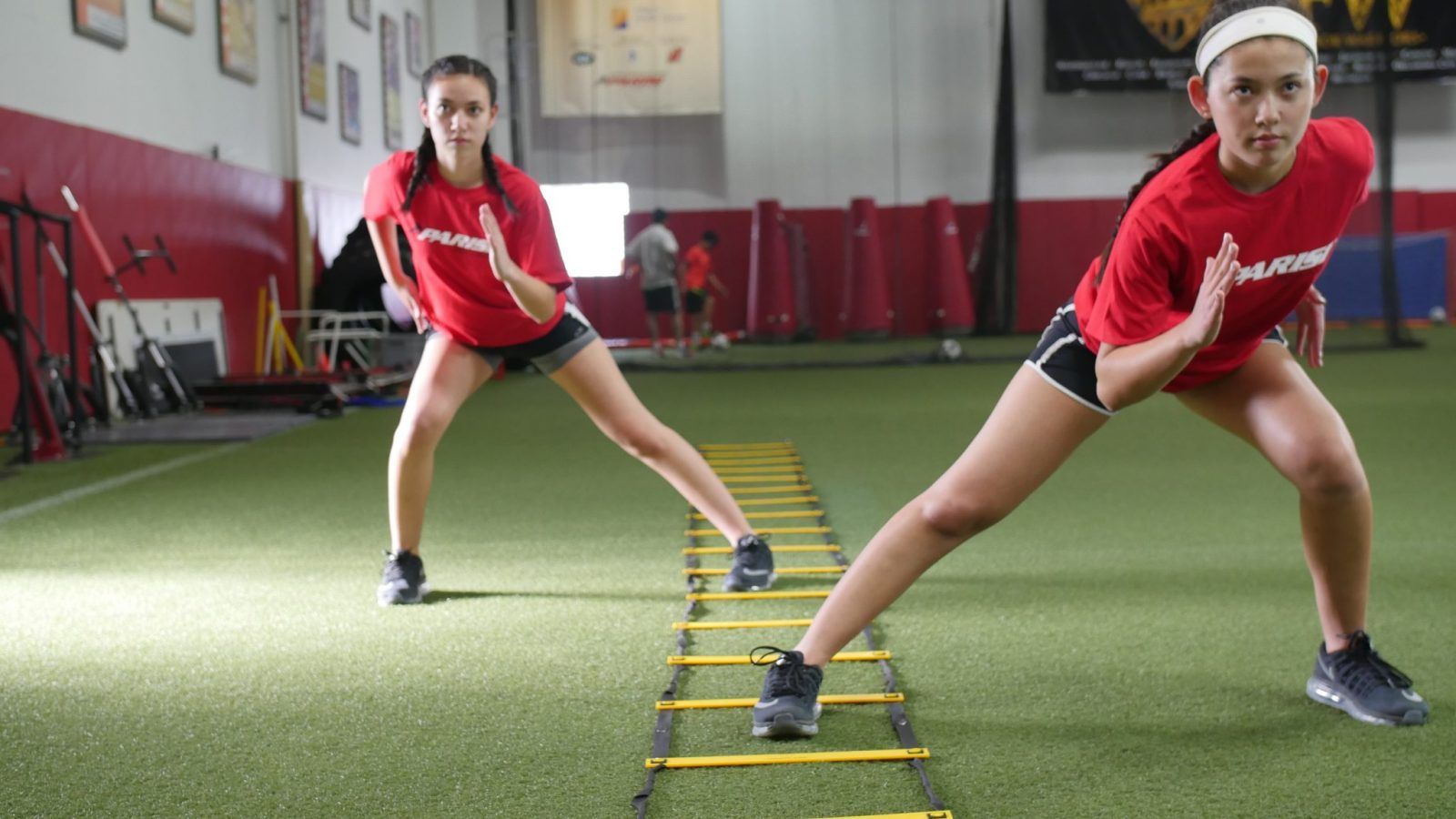 Sports performance training of two young female athletes on a grassy turf