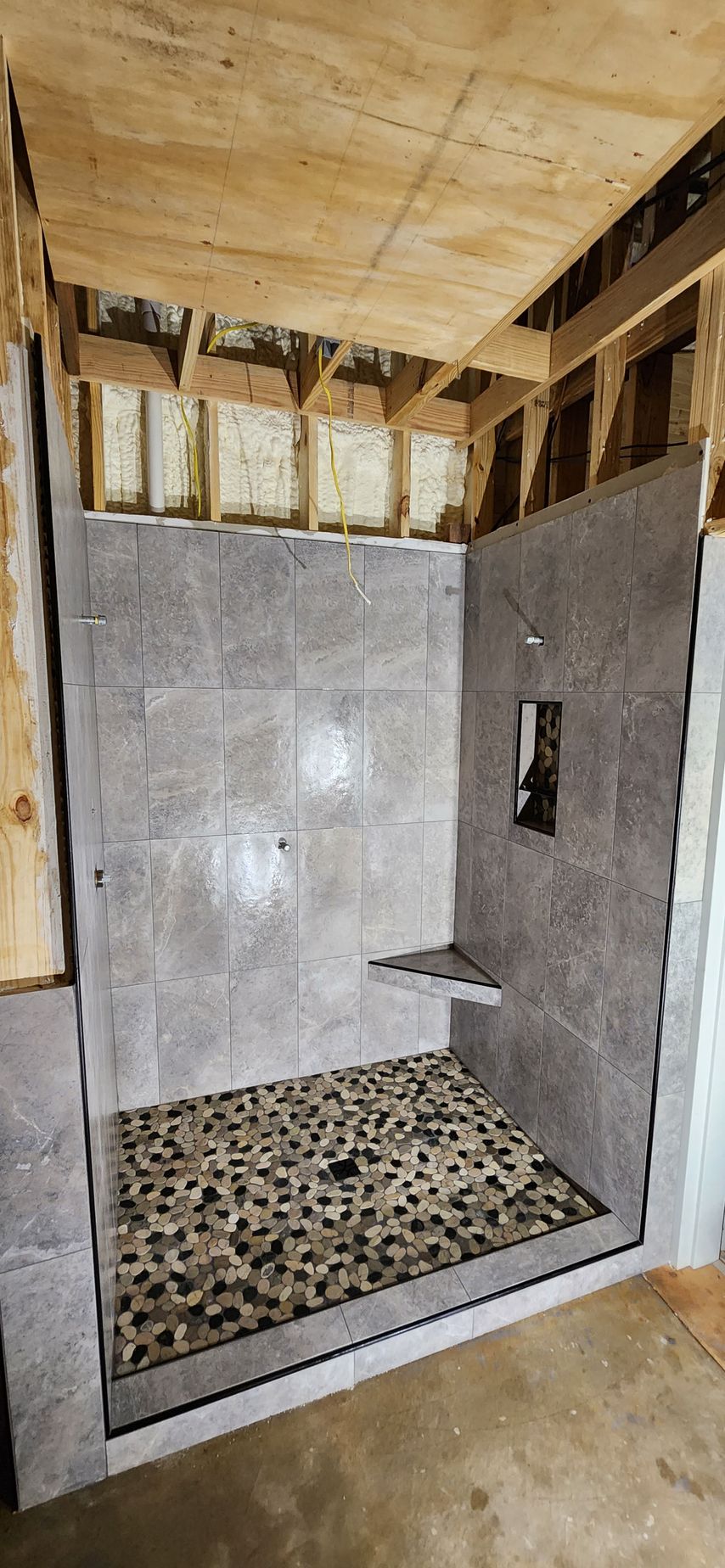 A bathroom with a walk in shower under construction.