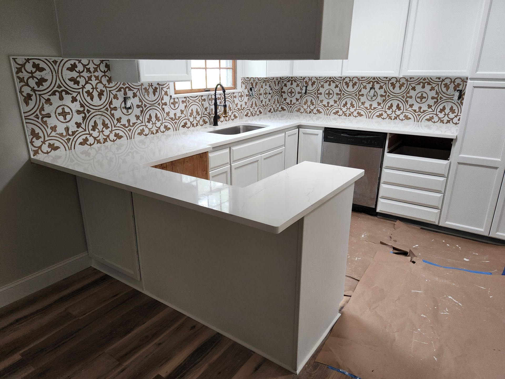 A kitchen with white cabinets , a sink , and a dishwasher.