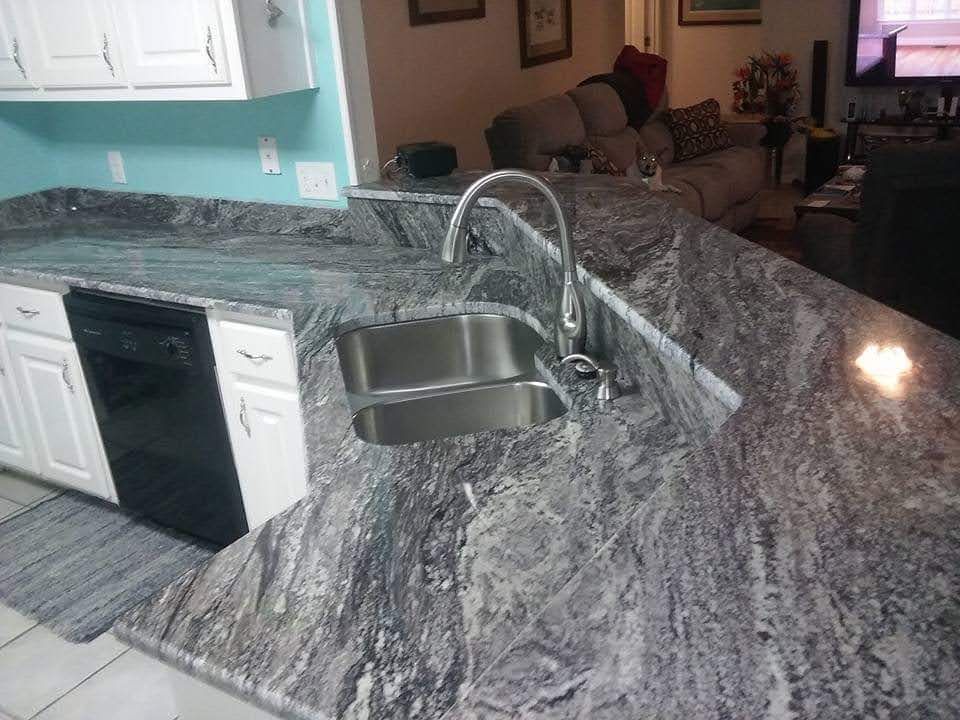 A kitchen with granite counter tops and a stainless steel sink.