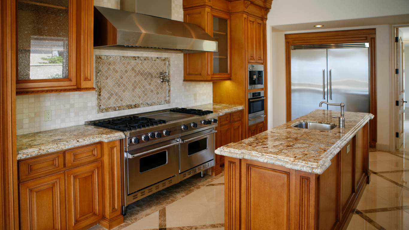 A kitchen with stainless steel appliances , granite counter tops , and wooden cabinets.