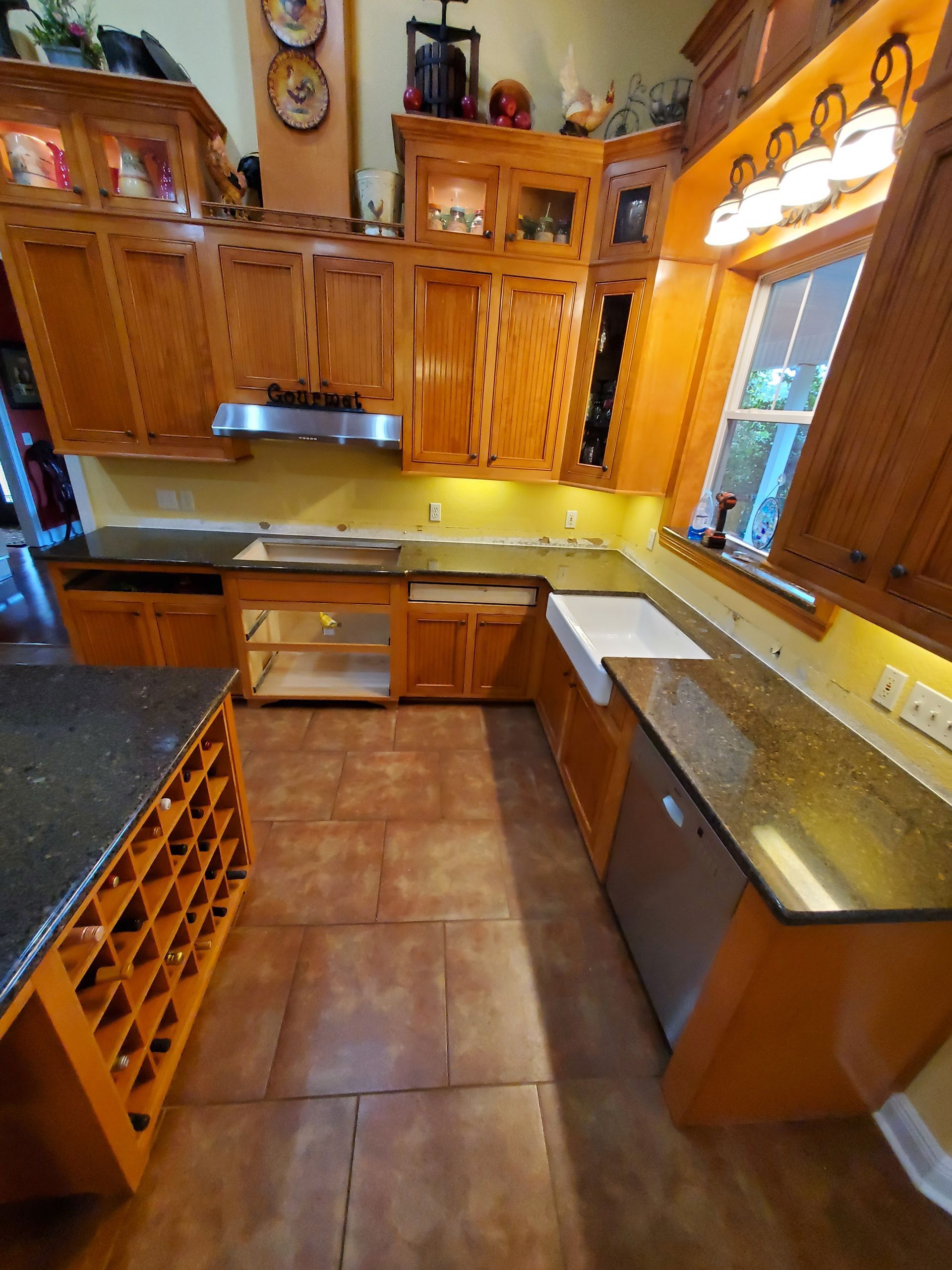A kitchen with wooden cabinets , granite counter tops , stainless steel appliances and a wine rack.