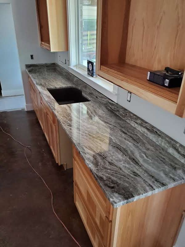 A kitchen with granite counter tops and wooden cabinets.