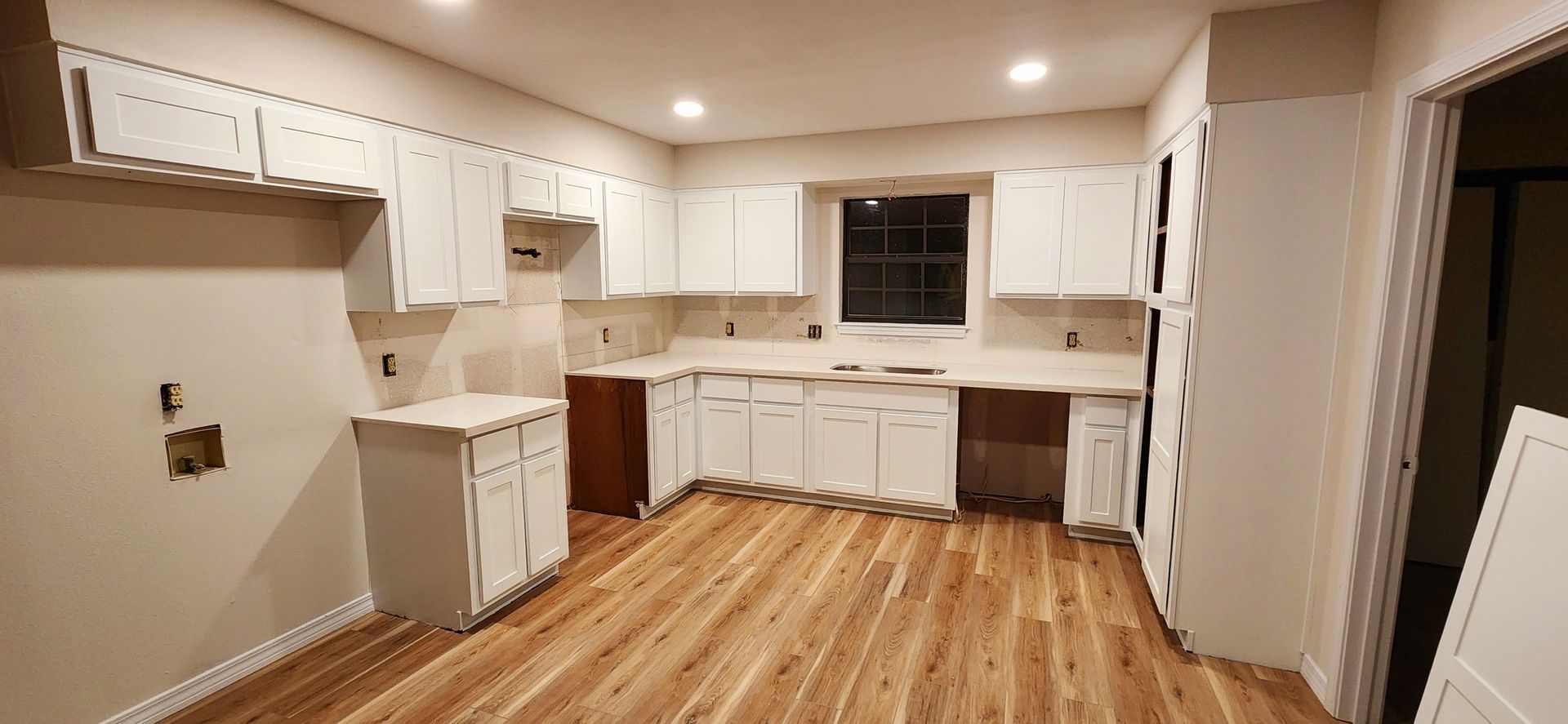 A kitchen with white cabinets and hardwood floors is being remodeled.
