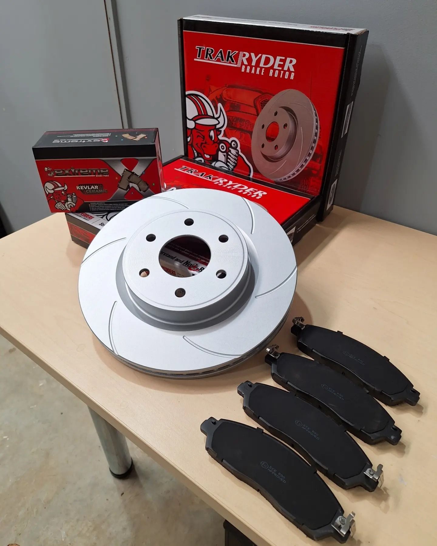 A brake disc and pads are sitting on a wooden table.