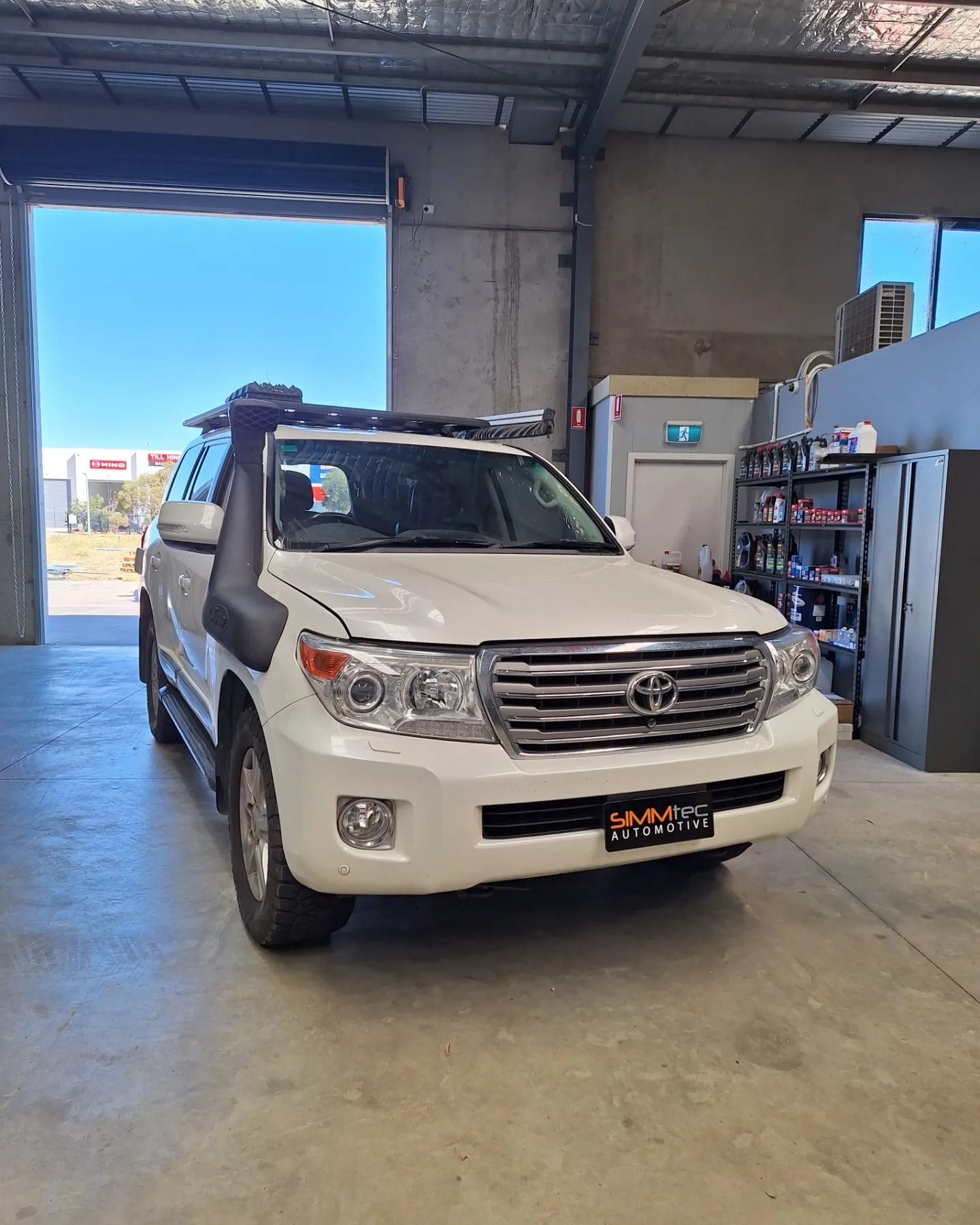 A white toyota land cruiser is parked in a garage.