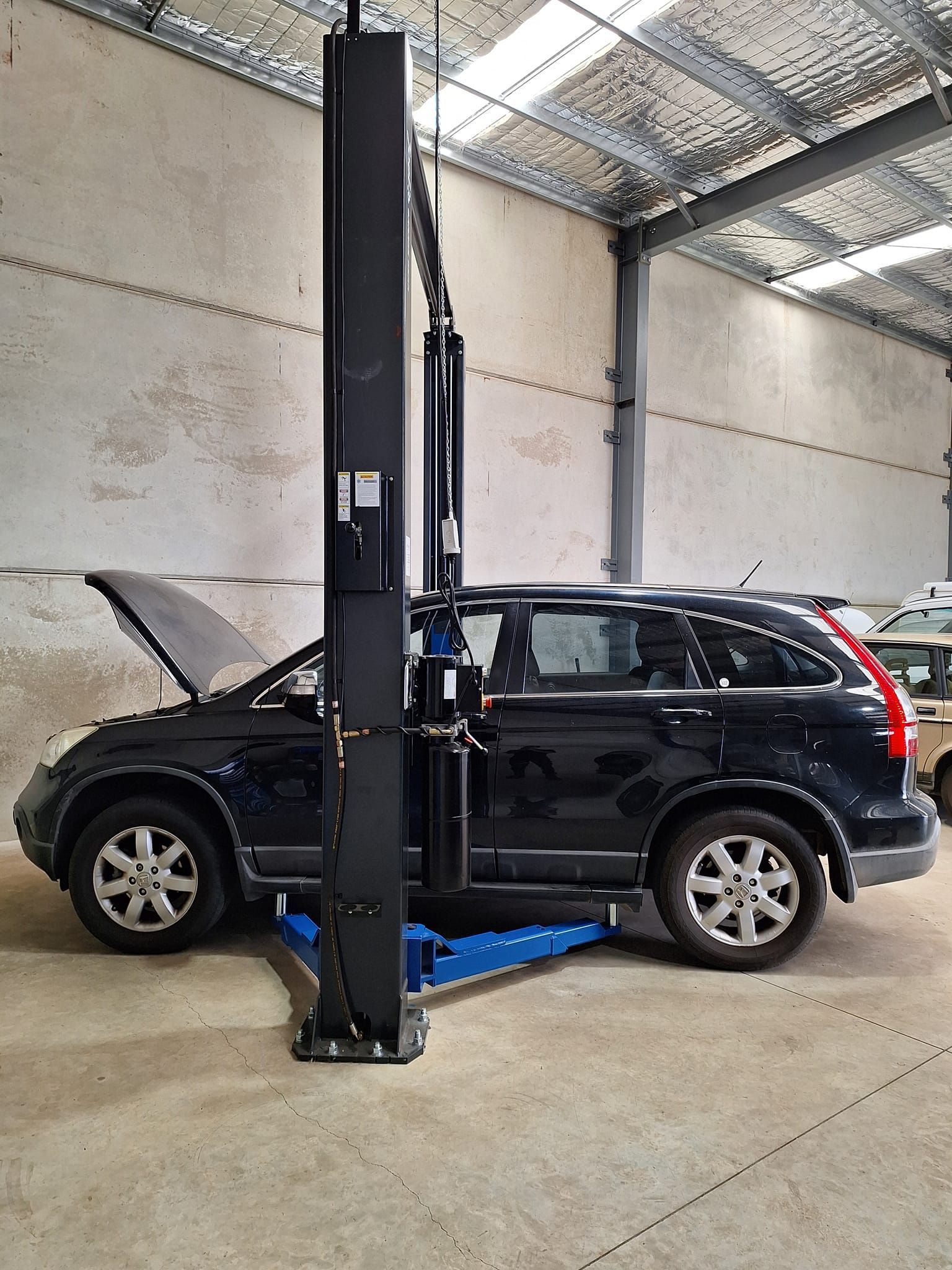 A black suv is parked on a lift in a garage.