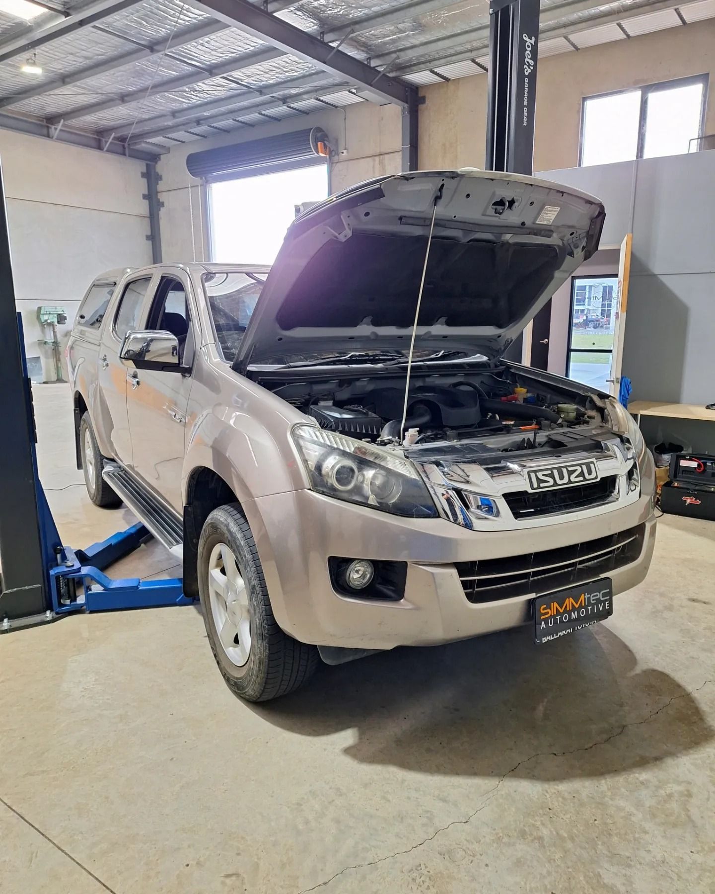 A car with the hood up is parked in a garage.