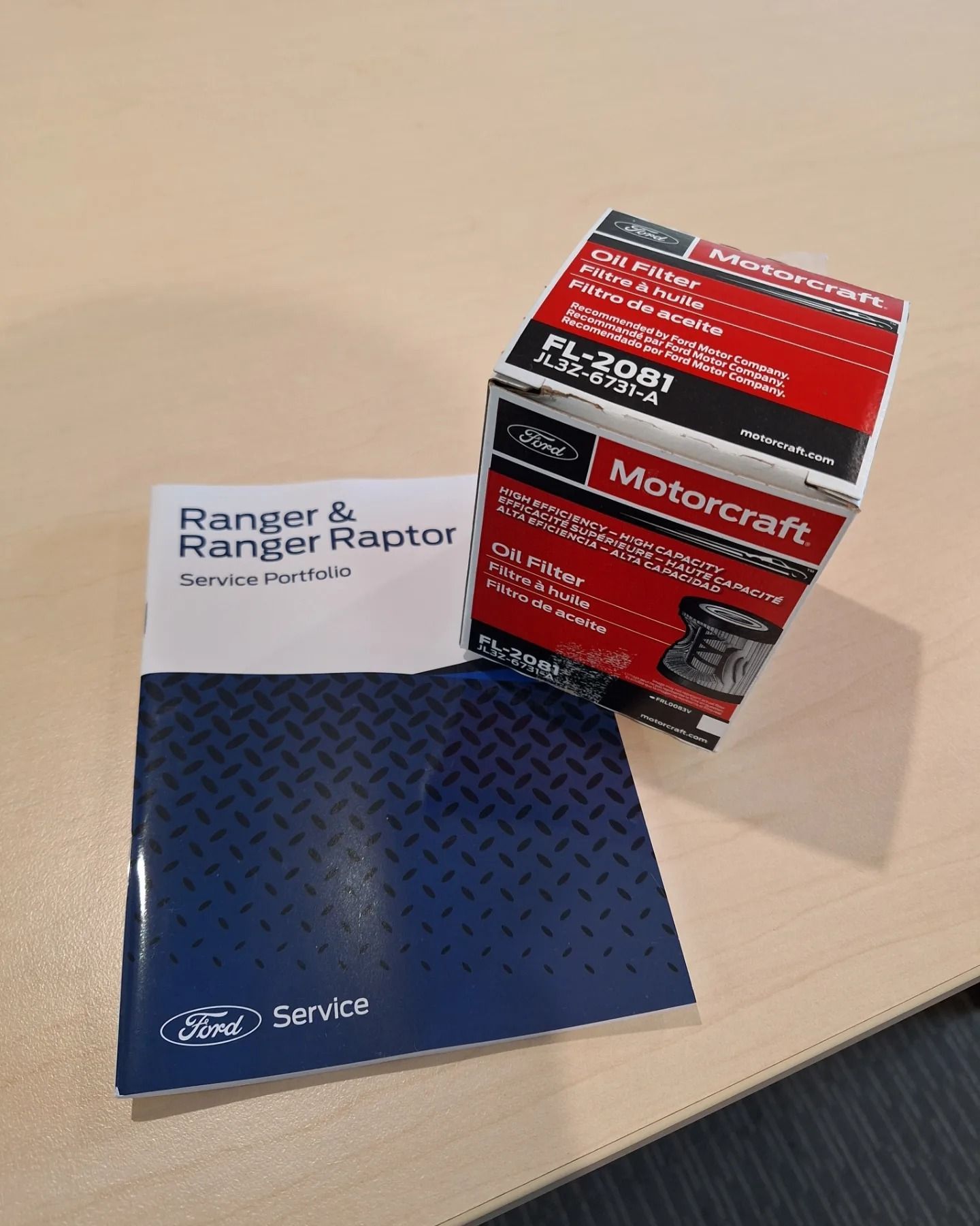 A box of ranger and raptor parts is sitting on a table next to a service manual.