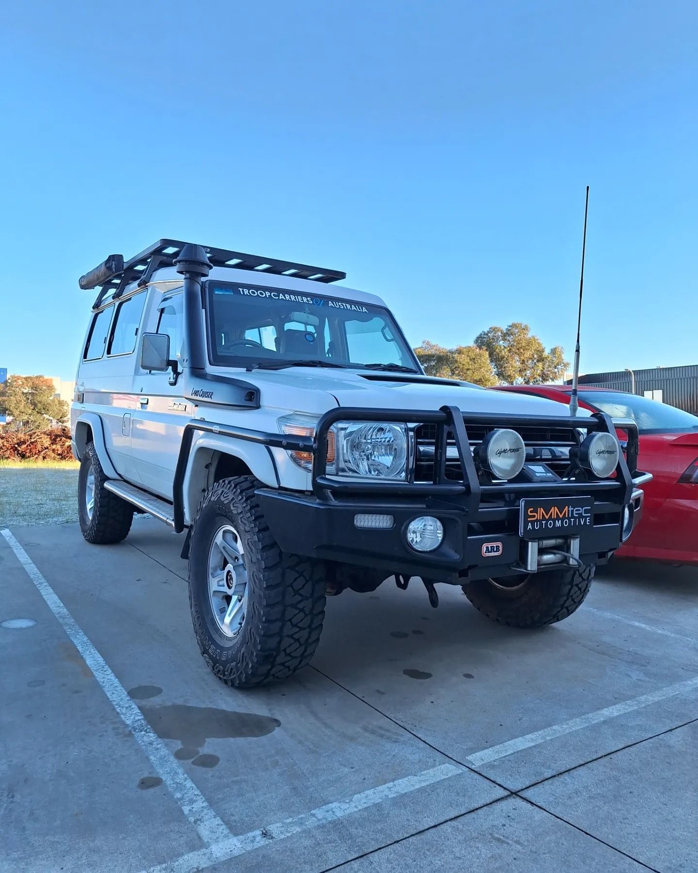 A white suv is parked in a parking lot next to a red car.