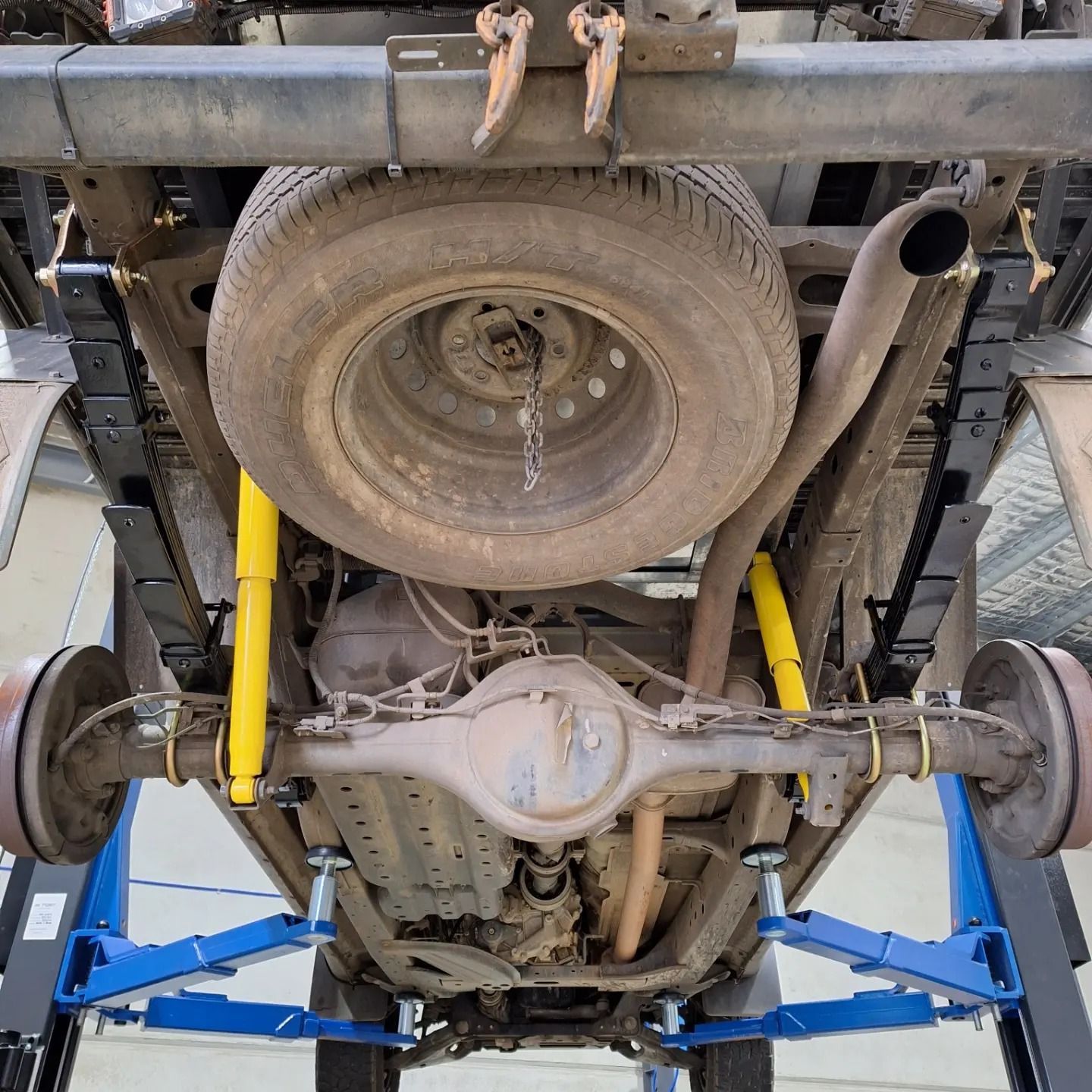 The underside of a truck is shown on a lift