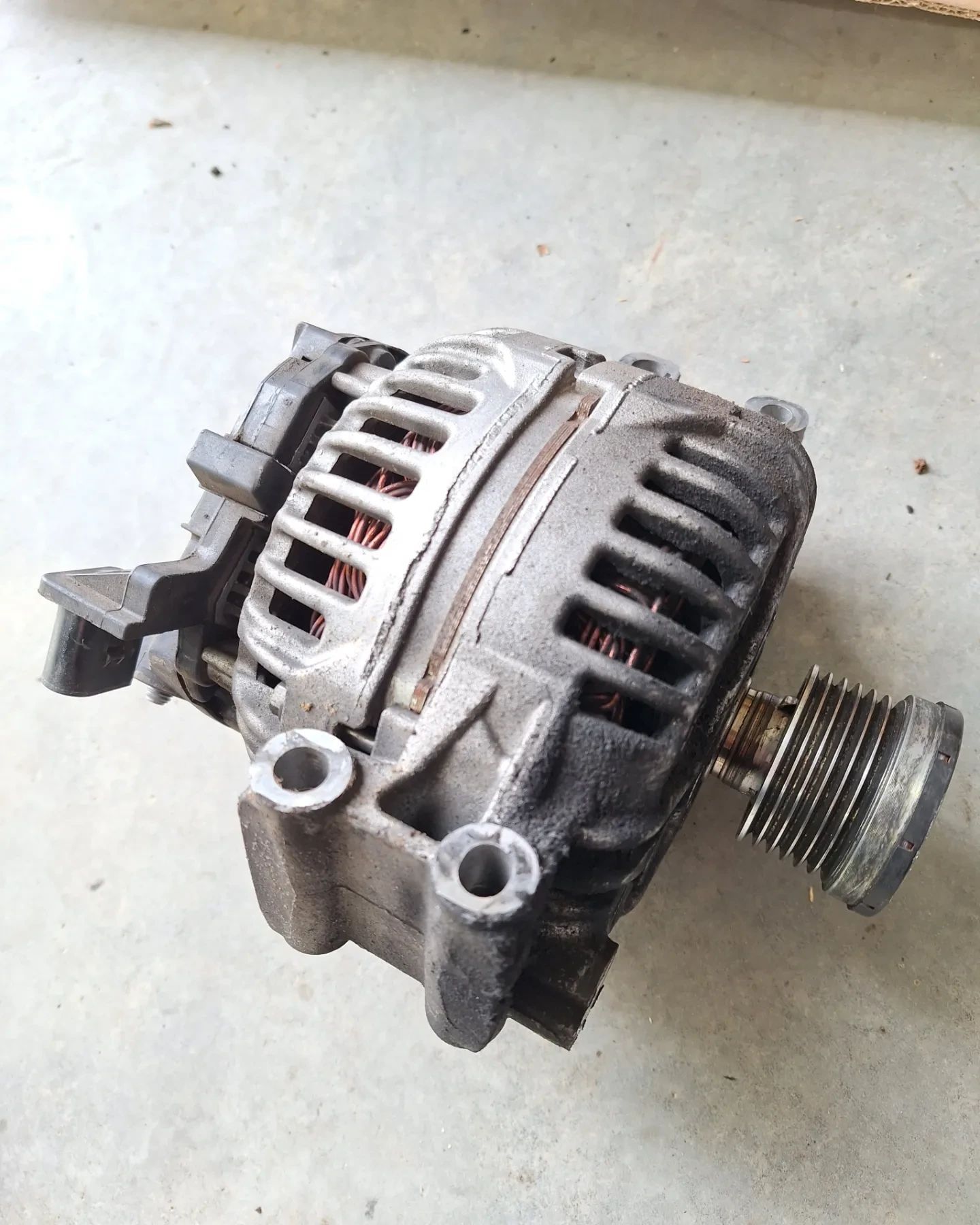 A close up of an alternator on a concrete surface.