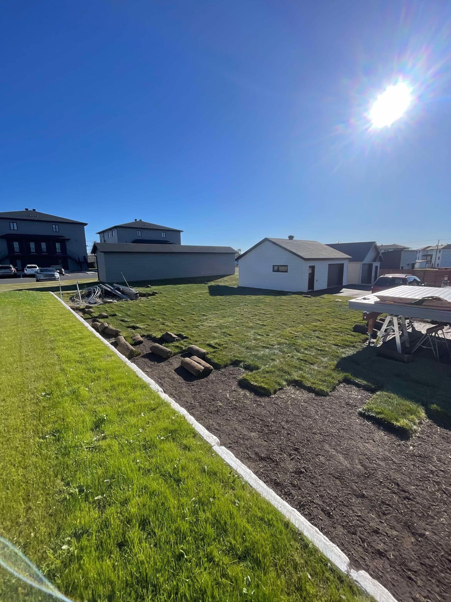 Un grand champ herbeux avec une maison en arrière-plan.