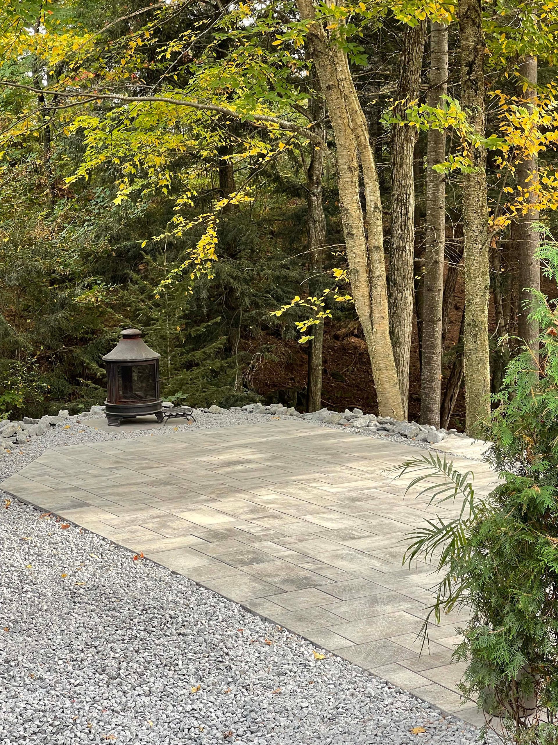 Une allée de gravier menant à une lanterne au milieu d'une forêt.