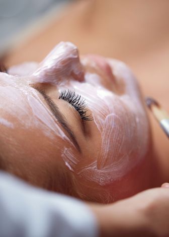 a woman is getting a white mask on her face