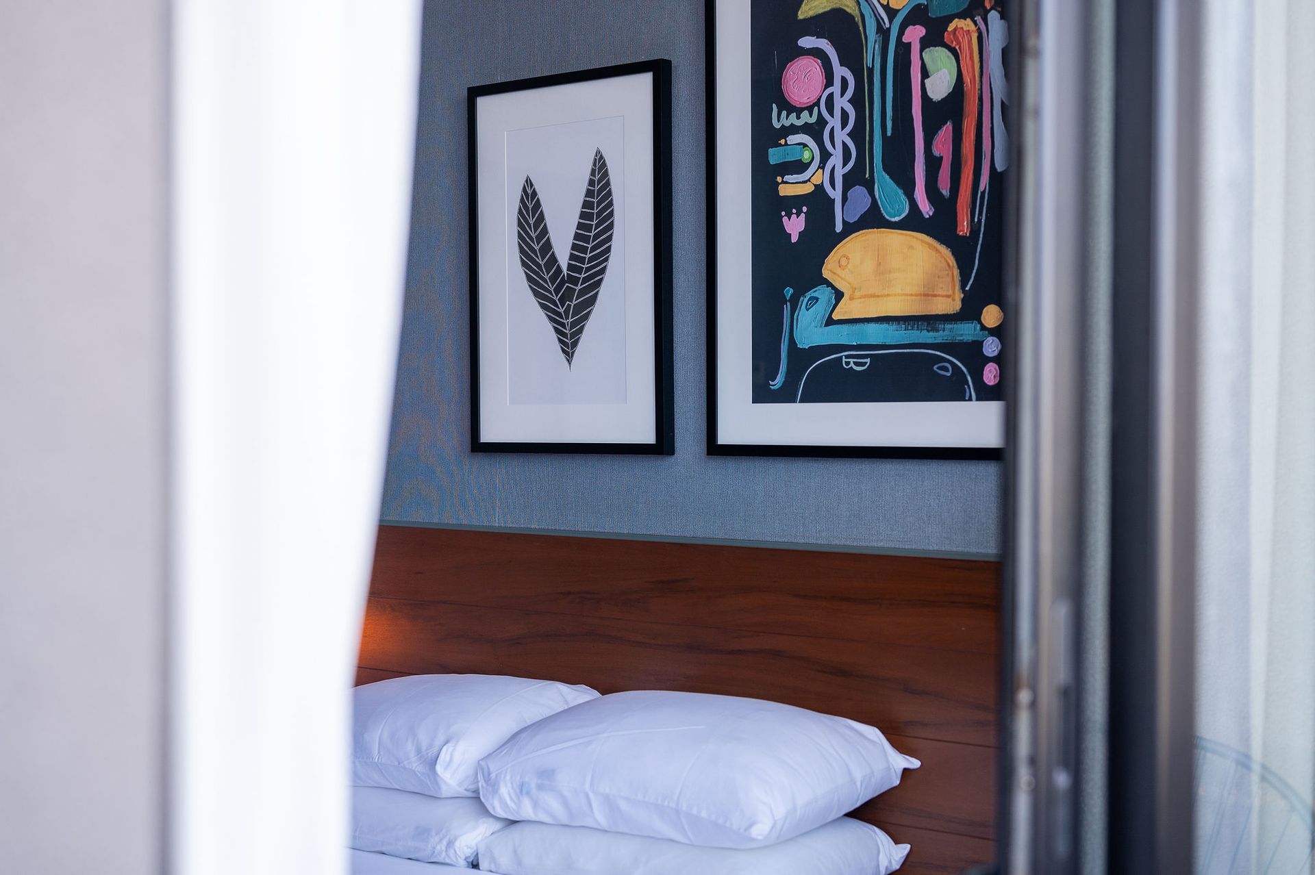 A bedroom with a bed , paintings on the wall , and a window.