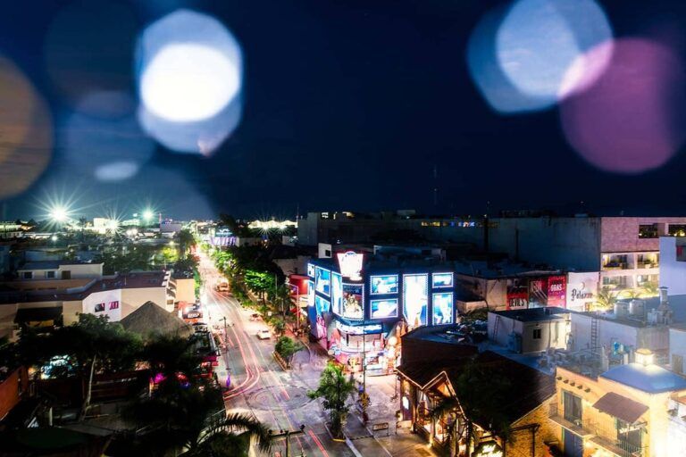 An aerial view of a city at night with a lot of lights on the buildings.