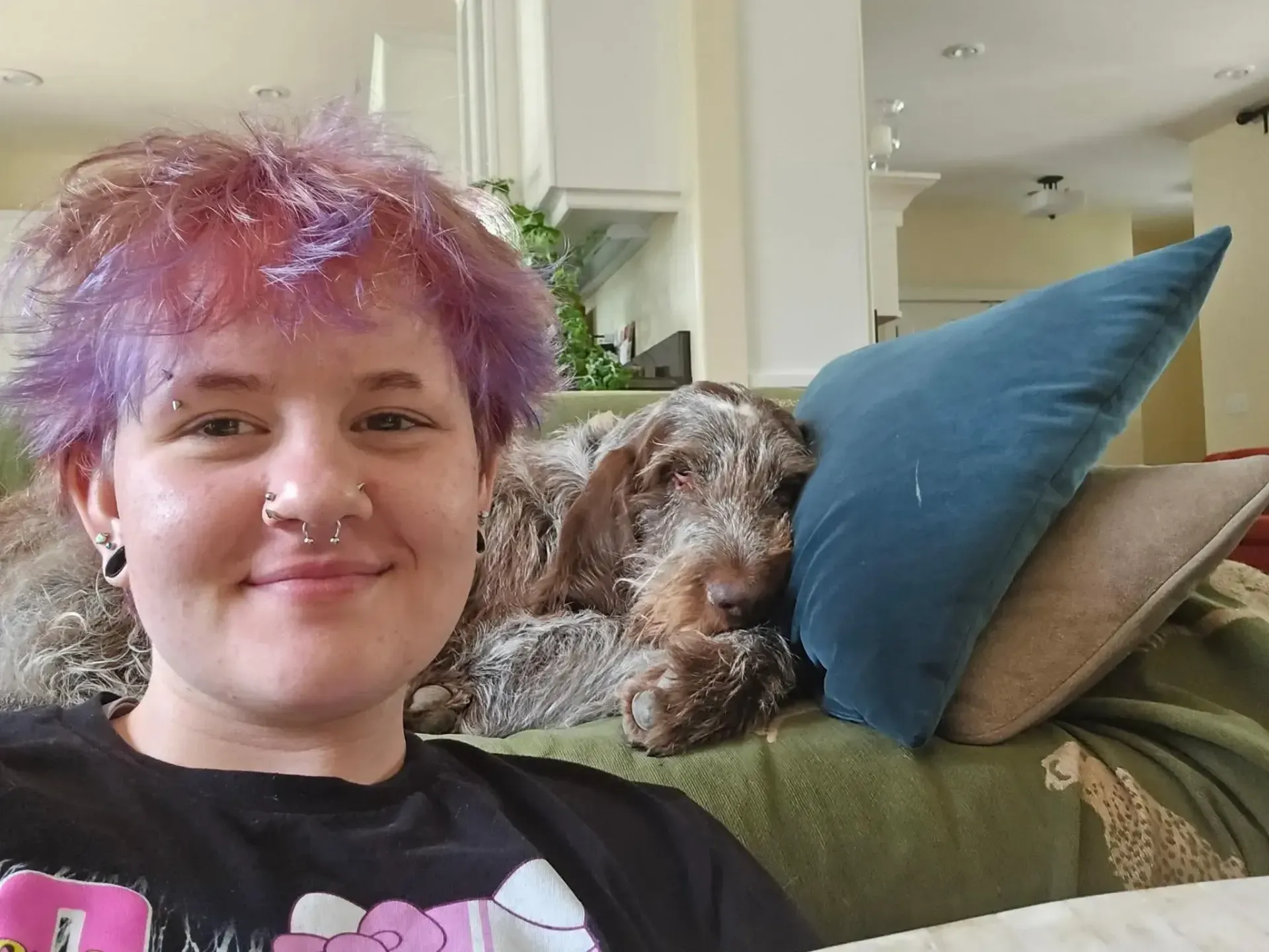 Dog walker and pet sitter Victori sitting next to a dog who's laying on a couch.