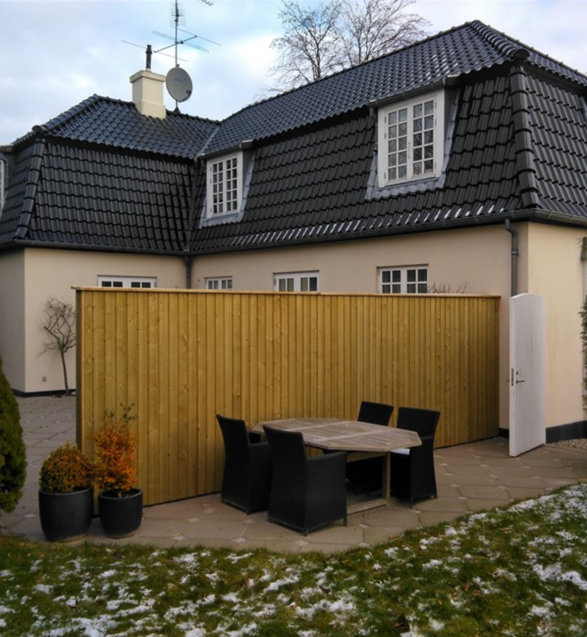 Et hus med et plankeværk og et bord og stole foran