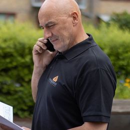En mand i sort skjorte taler i mobiltelefon