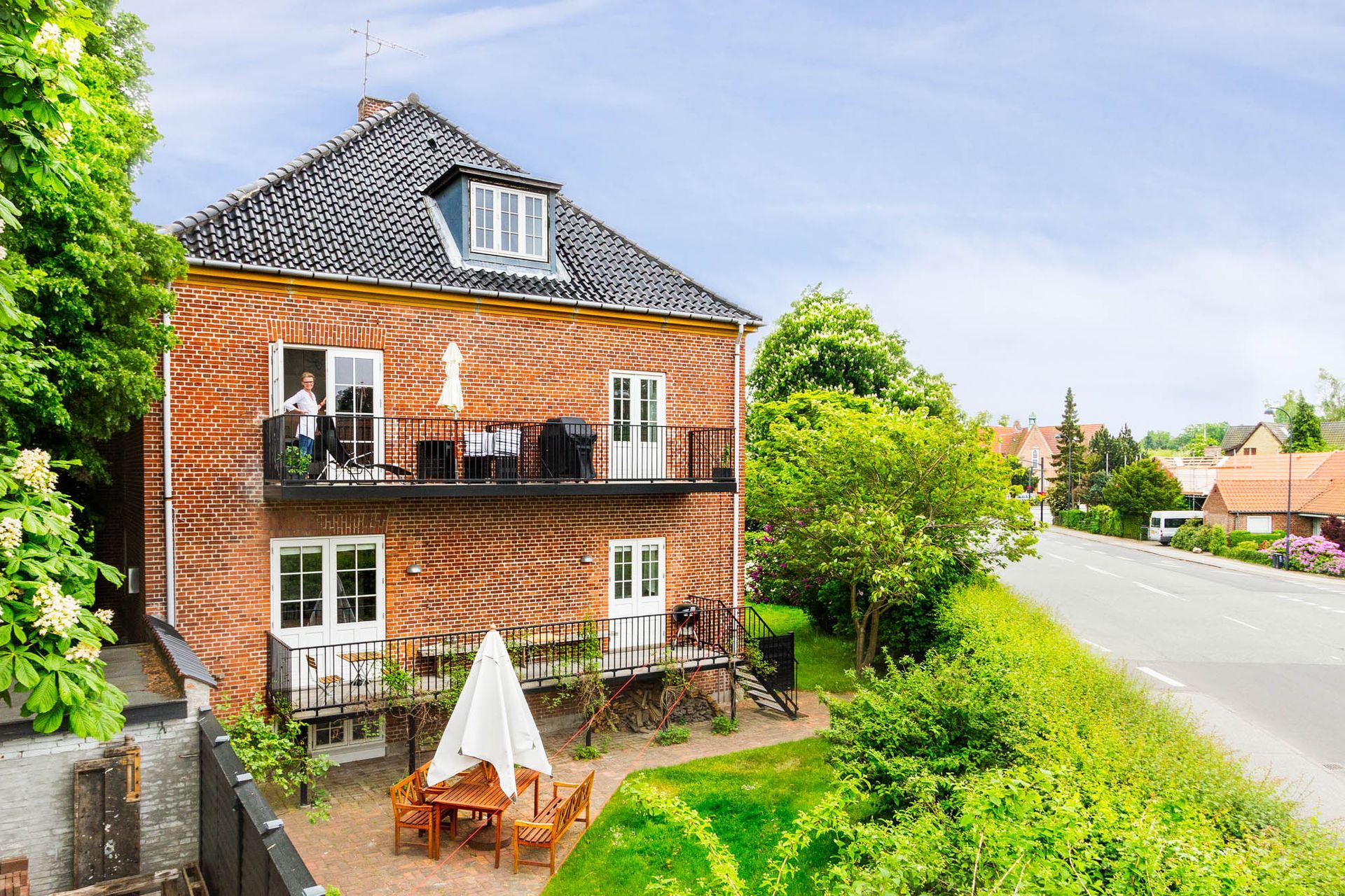 Et stort murstenshus med balkon og et bord og stole foran.