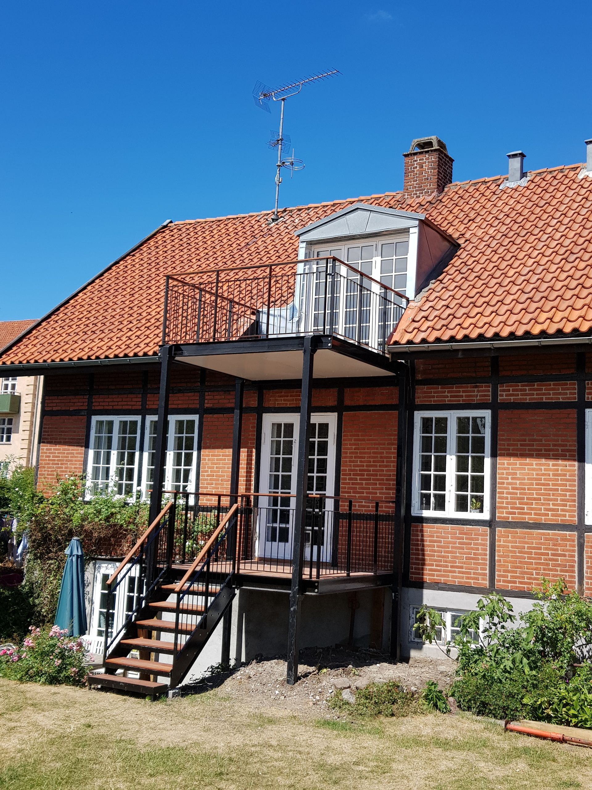 Et murstenshus med rødt tegltag og trapper