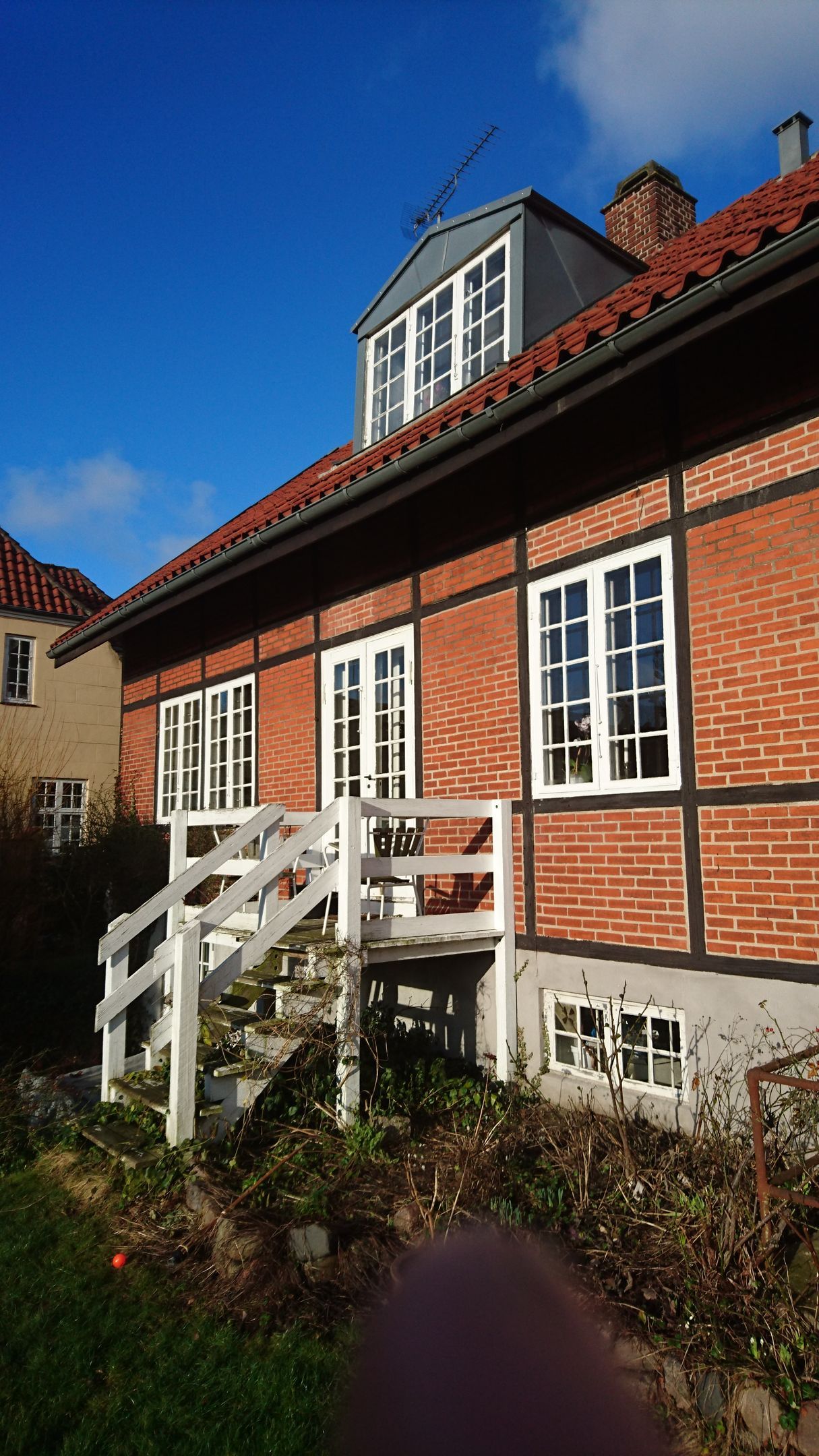 Et murstenshus med trapper der fører op til det og en balkon.