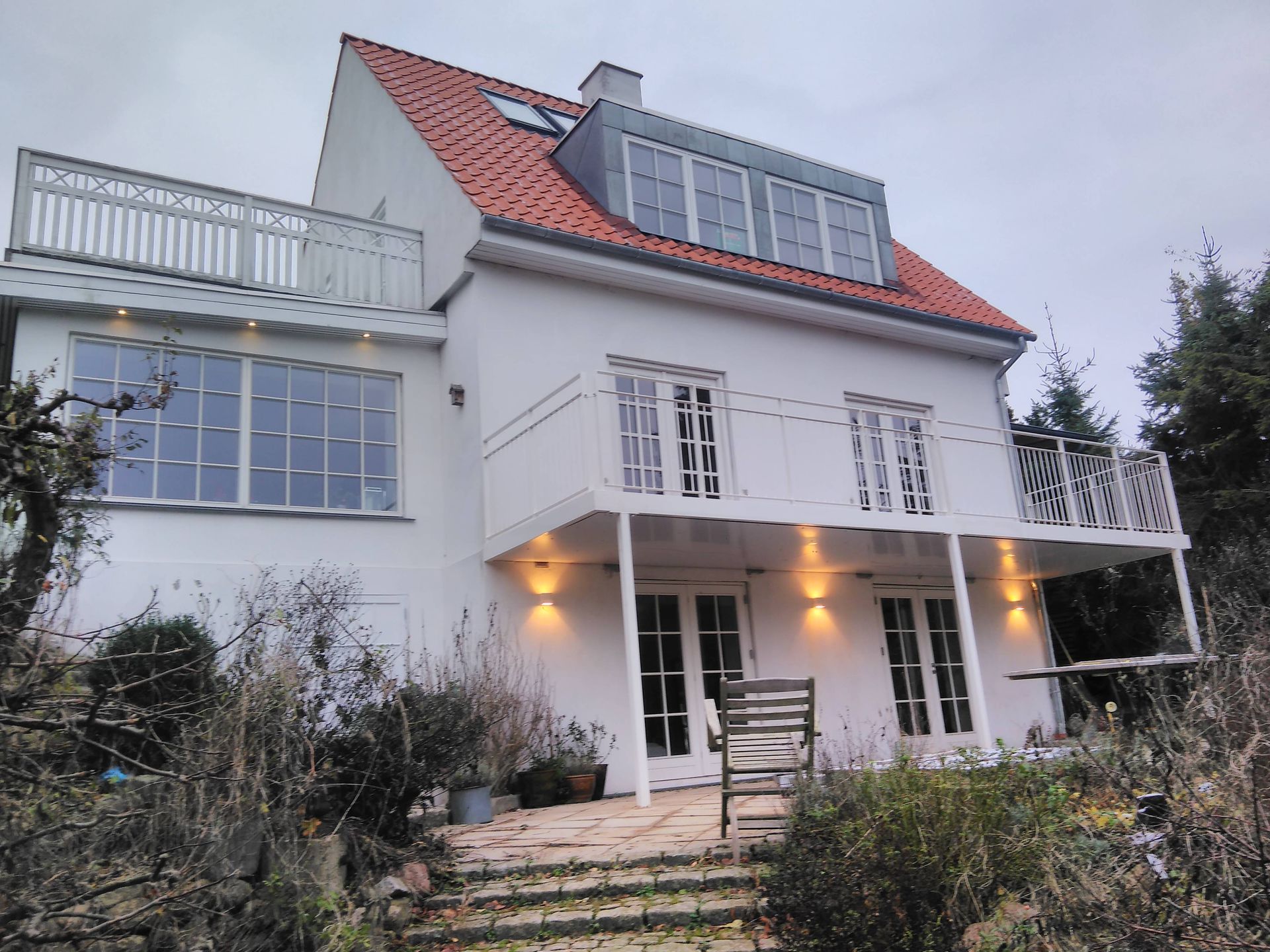 Et hvidt hus med rødt tag og balkon