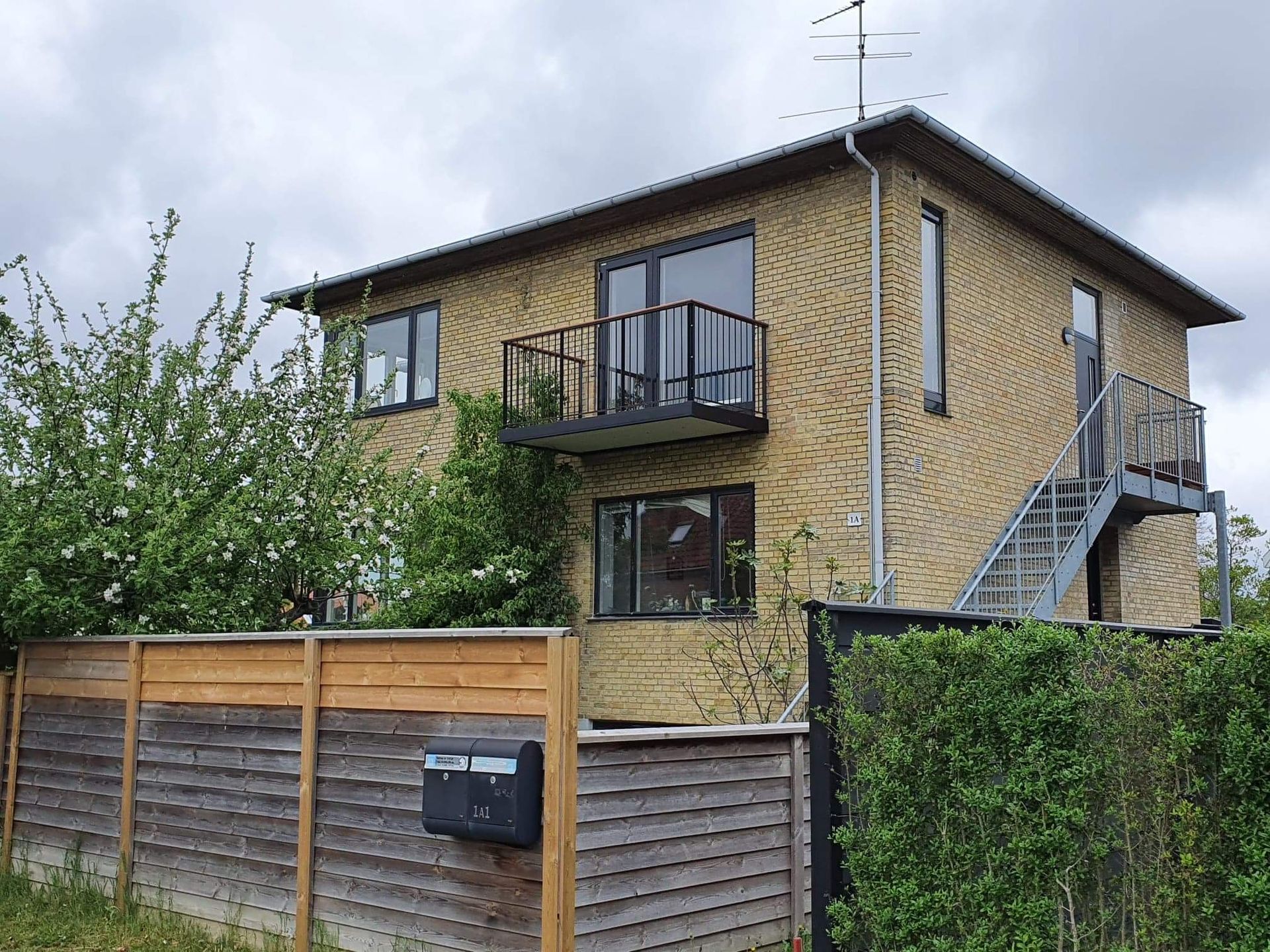 Et hus med et plankeværk og en postkasse foran