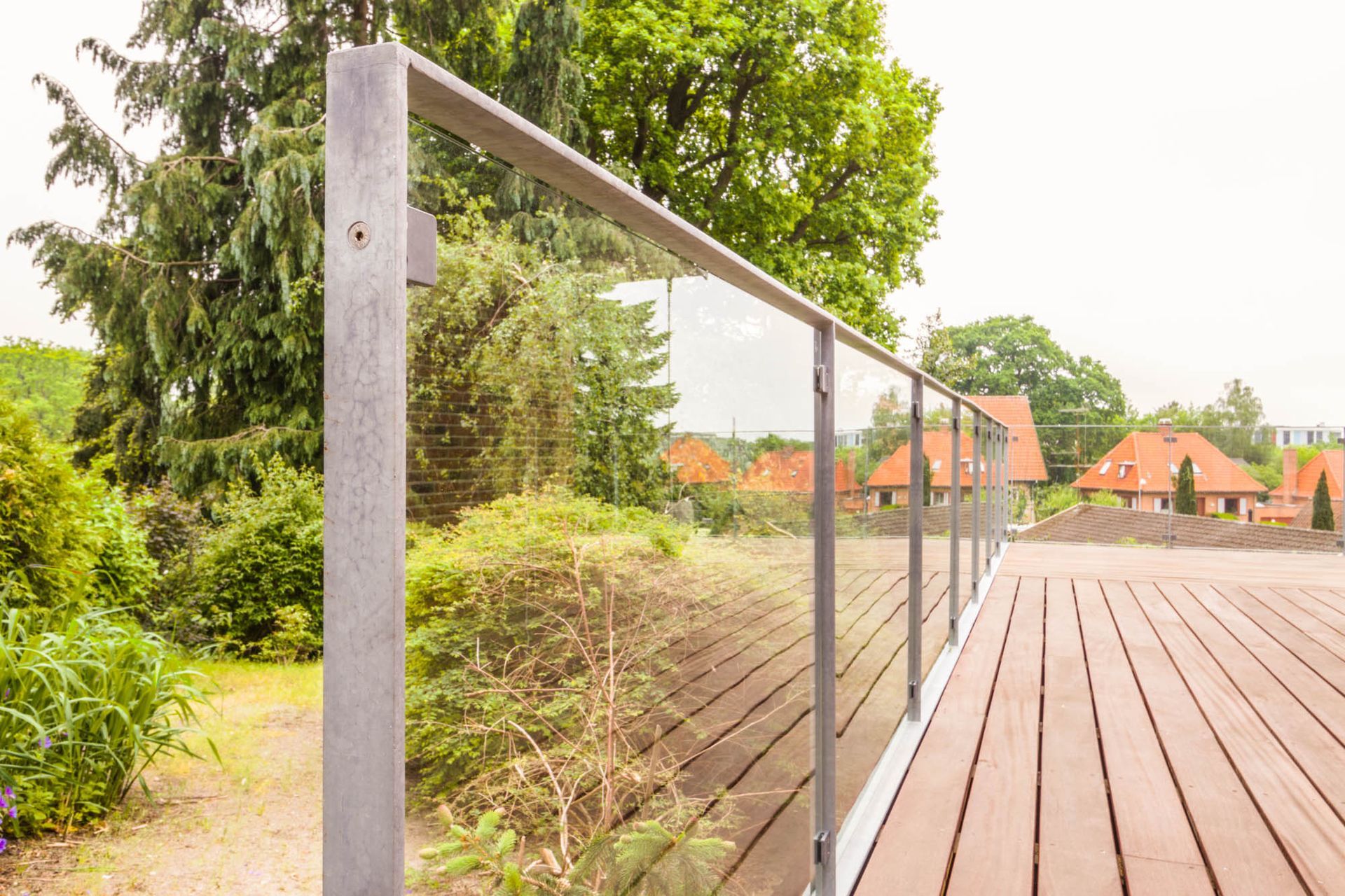 Et træterrasse med et glasrækværk og træer i baggrunden