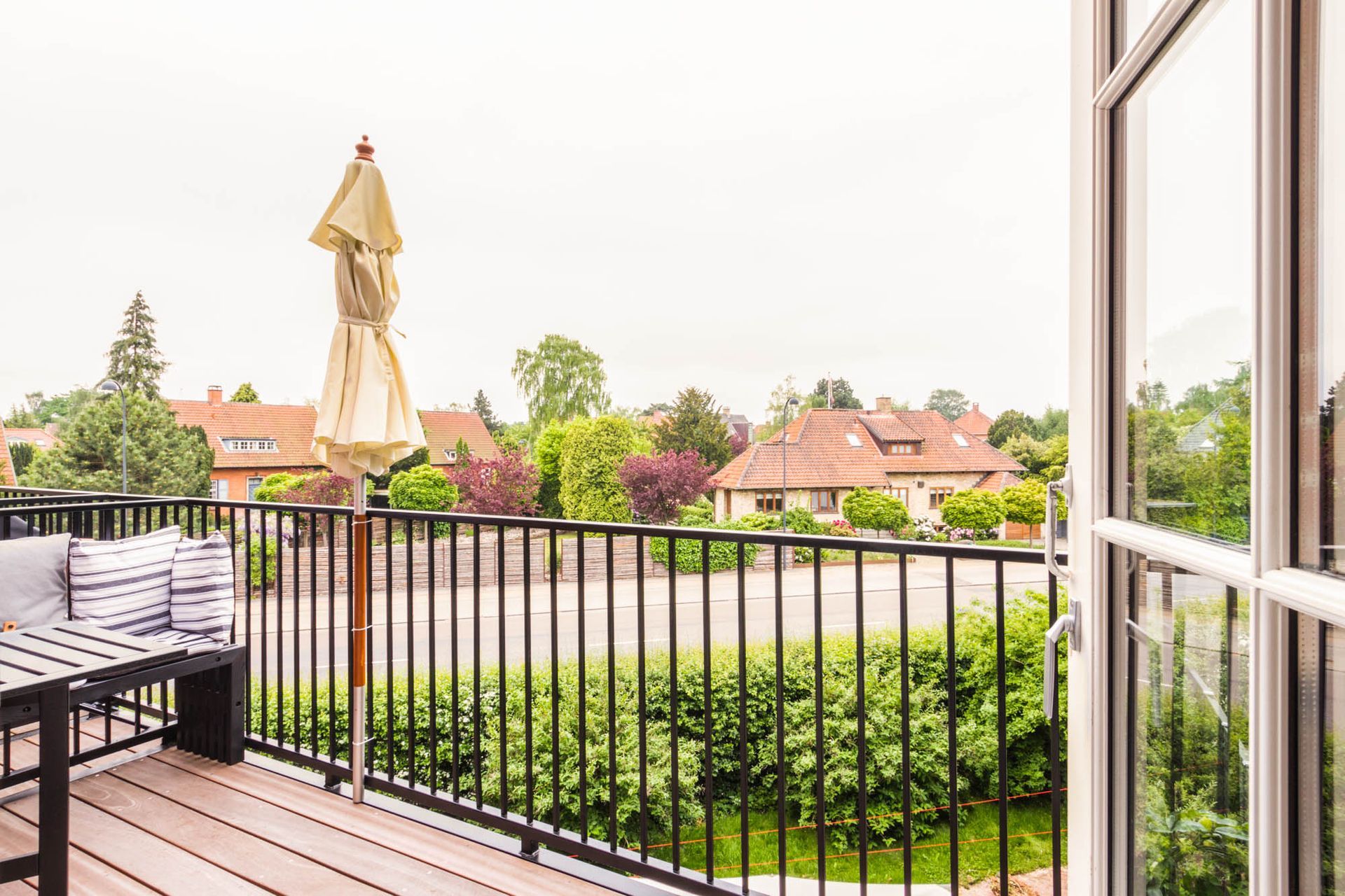 Der er en balkon med et bord og paraply på den.