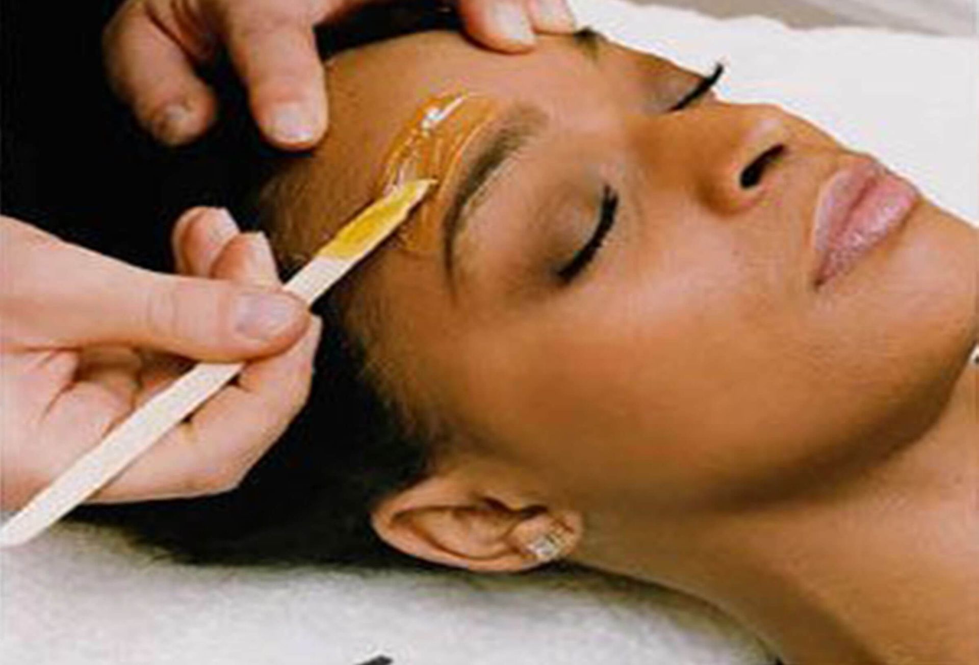 Woman with eyes closed, wearing gold under-eye patches. Close-up.