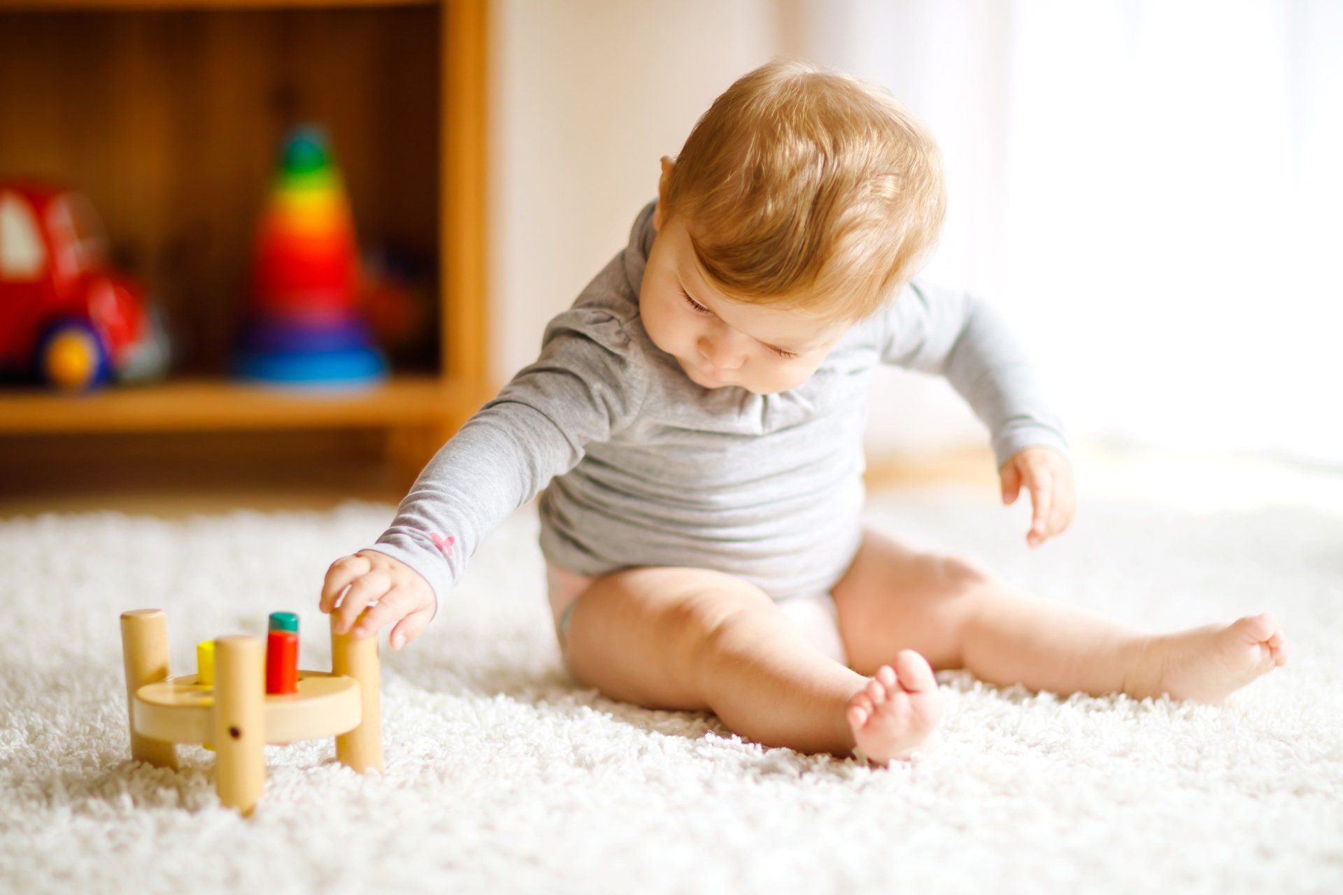 a baby reaching for a toy on the ground