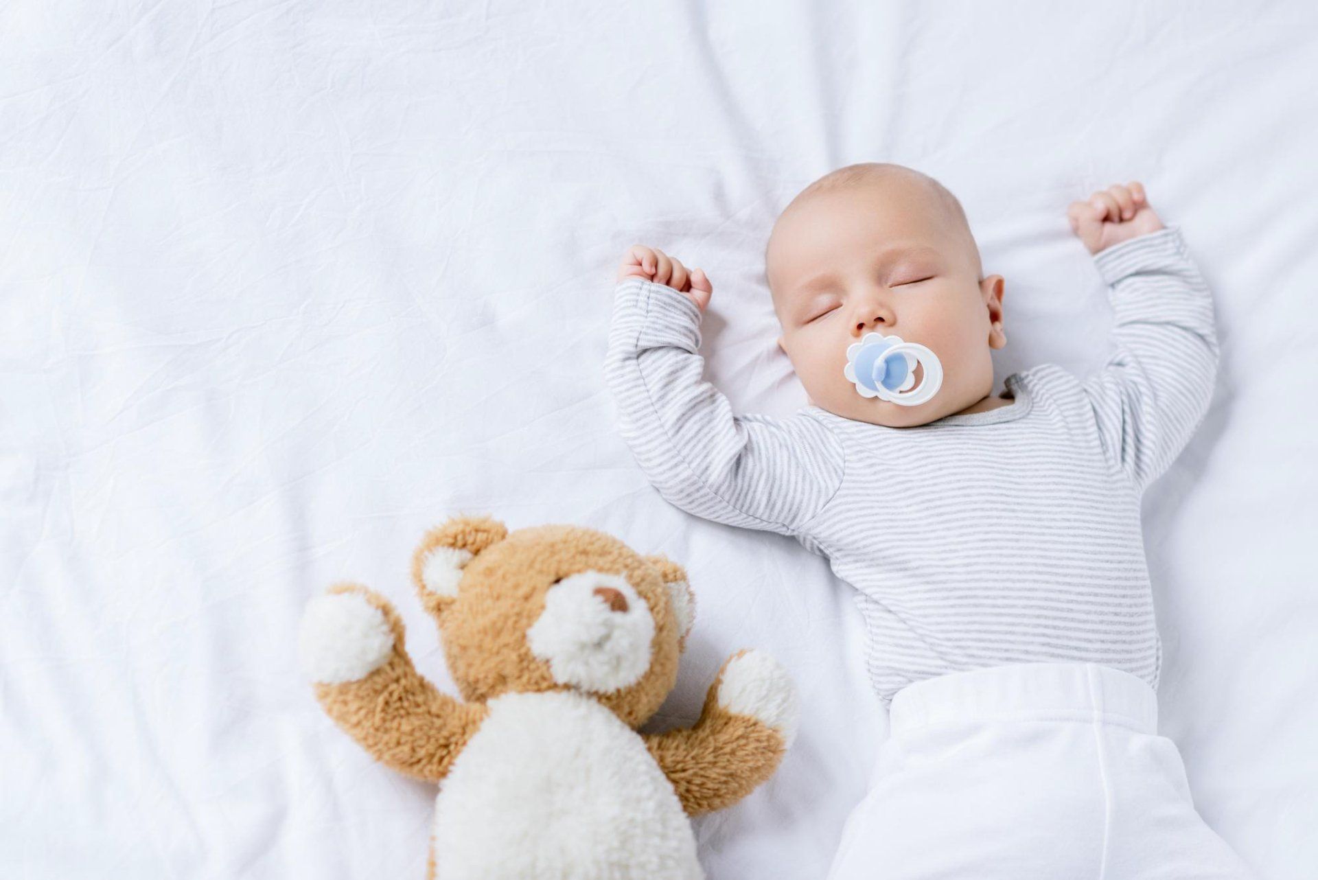 a sleeping baby and teddy bear