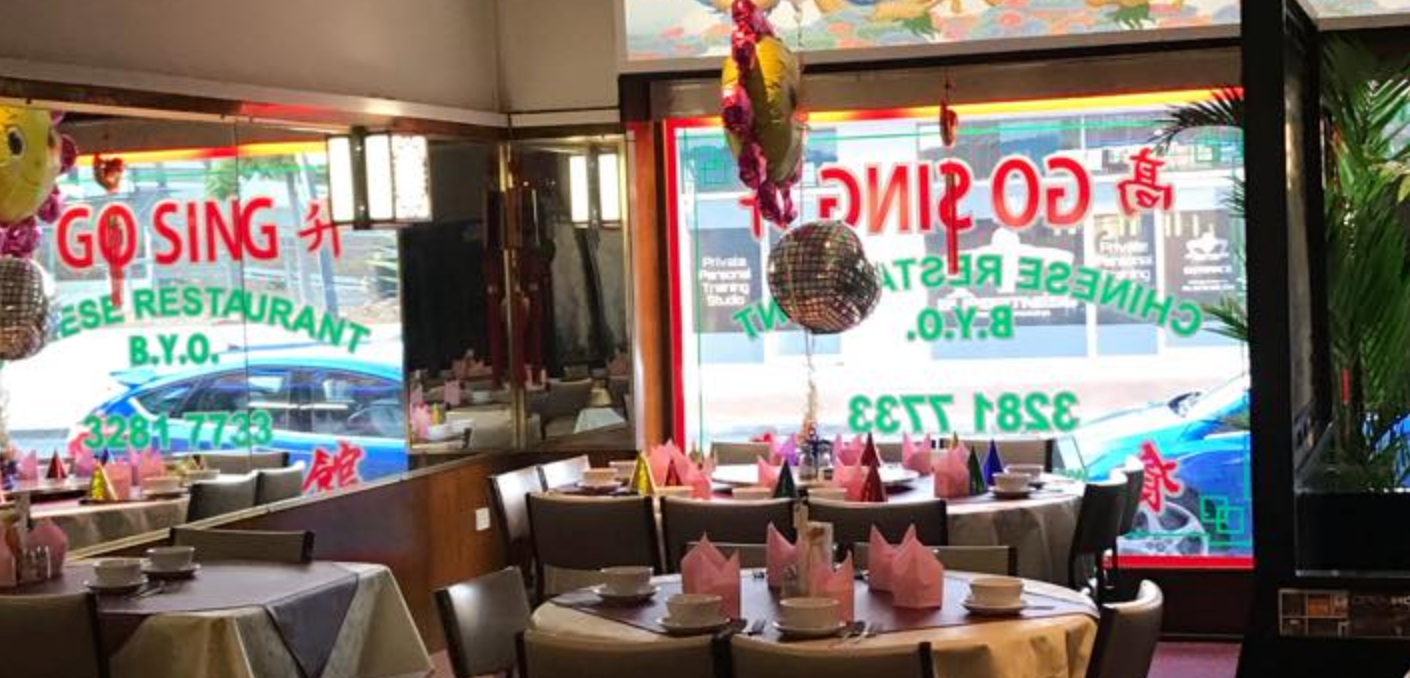 A restaurant with tables and chairs and balloons hanging from the ceiling.