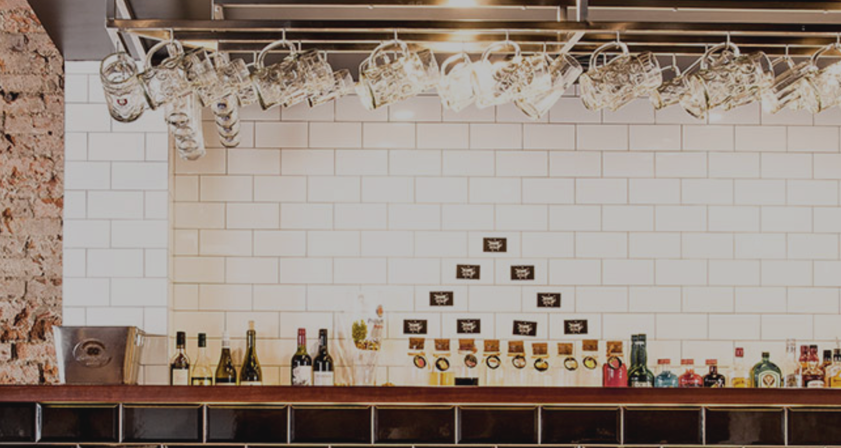 A bar with bottles and glasses hanging from the ceiling.