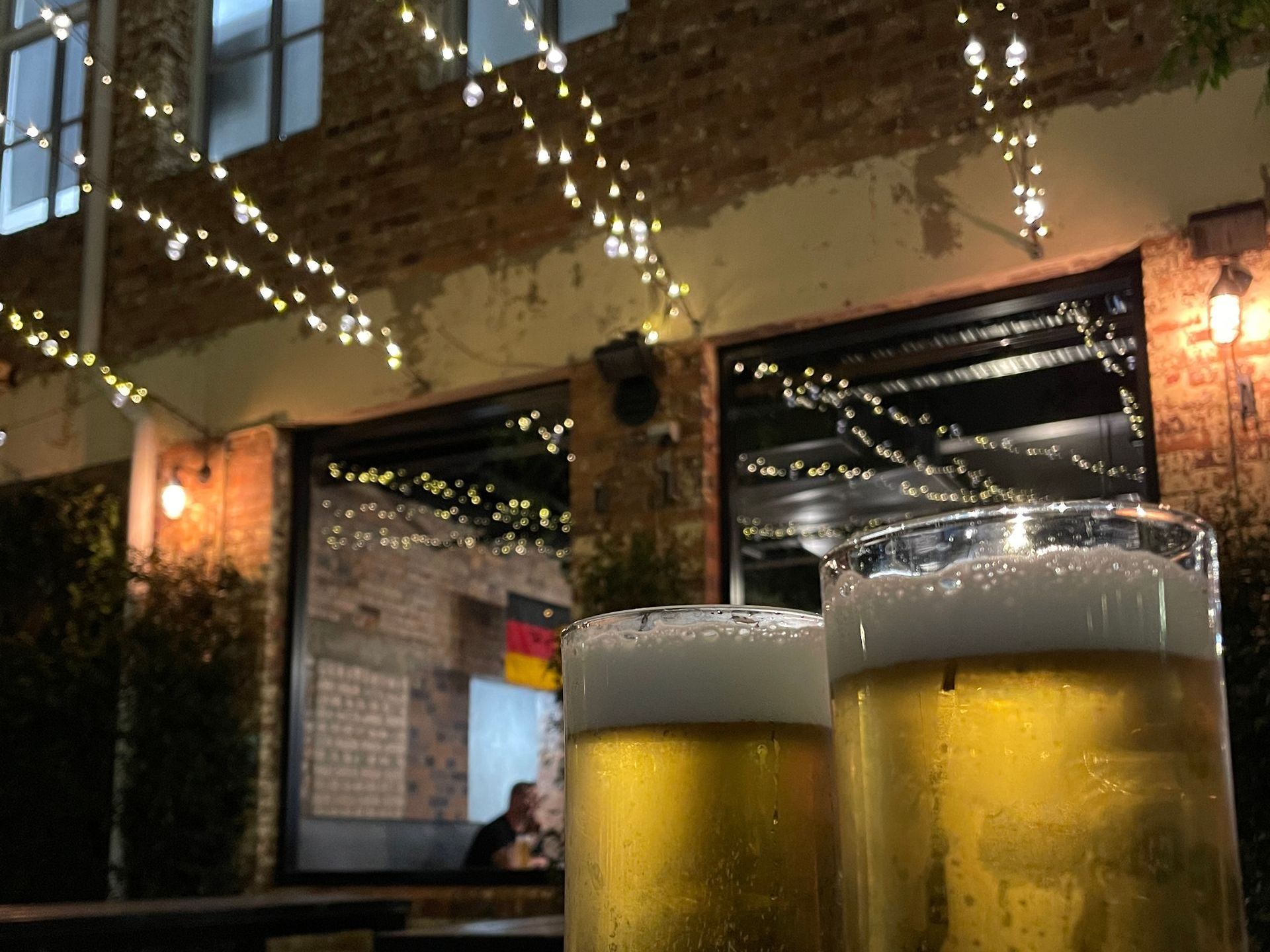 Two glasses of beer are on a table in front of a building