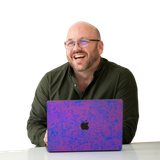 A man is smiling while using an apple laptop