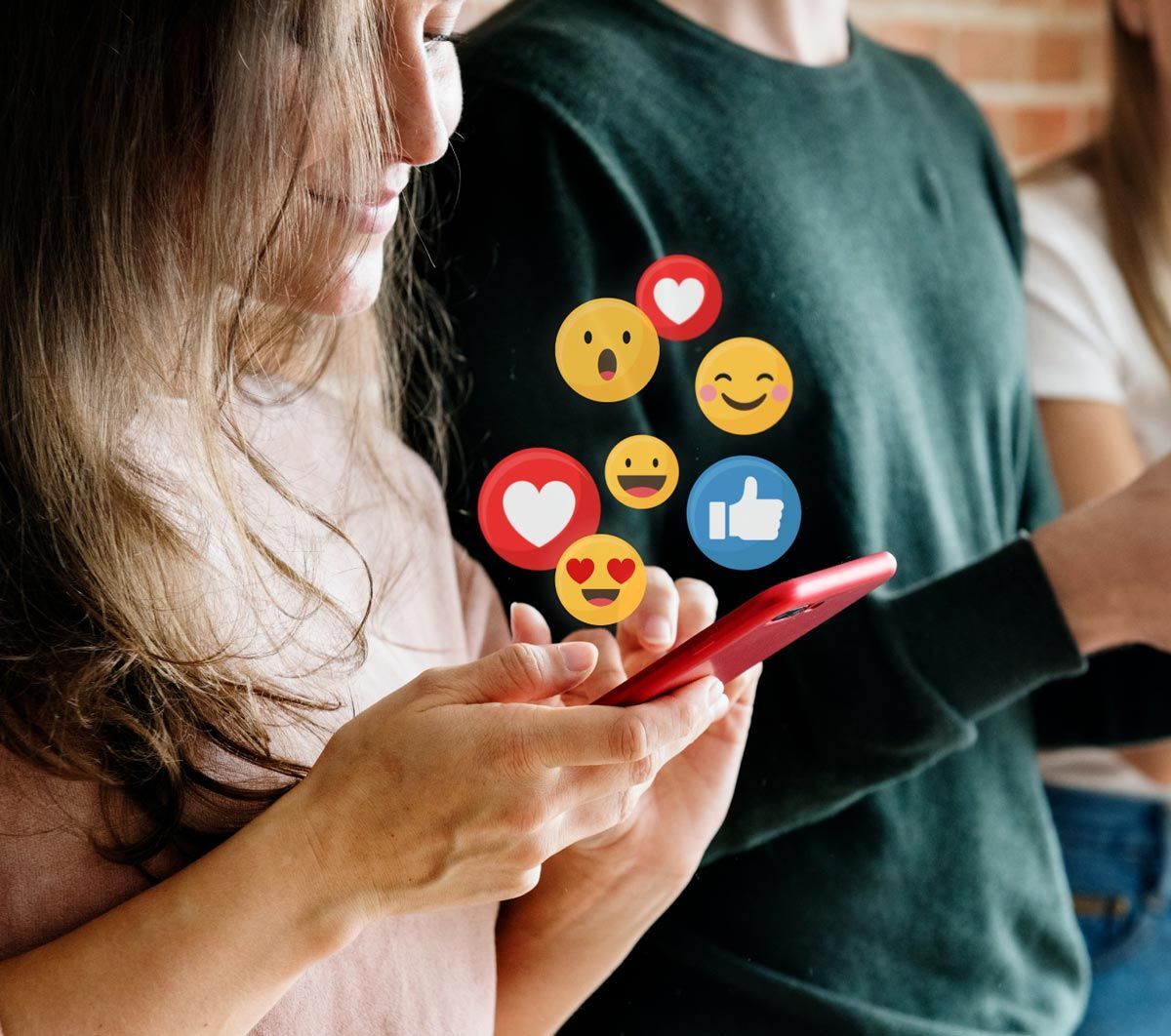 A woman is looking at a cell phone with smiley faces on it