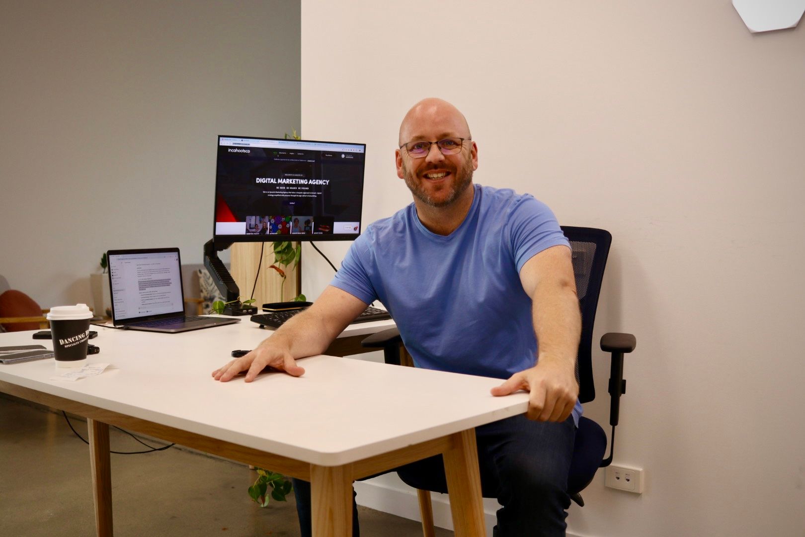 A man is sitting at a desk in front of a computer monitor.