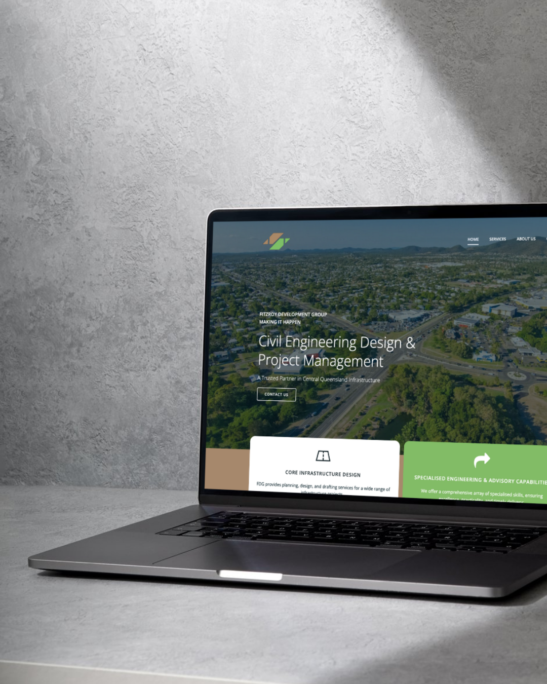 Laptop displaying a website for Landscaping Engineering Design & Project Management, with aerial view in background.