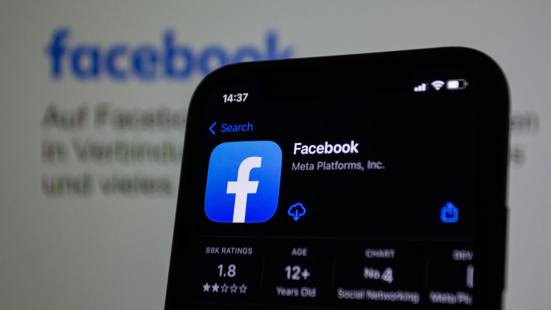Smartphone displaying the Facebook app logo against a background of the Facebook logo.