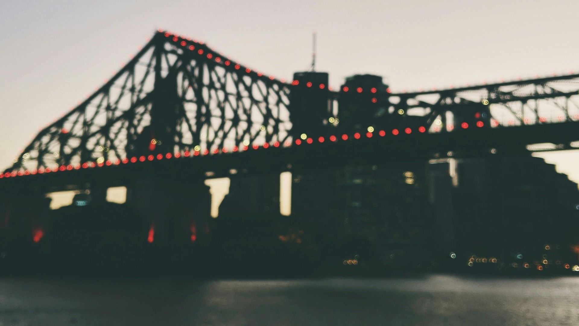 A blurry picture of a bridge over a body of water.