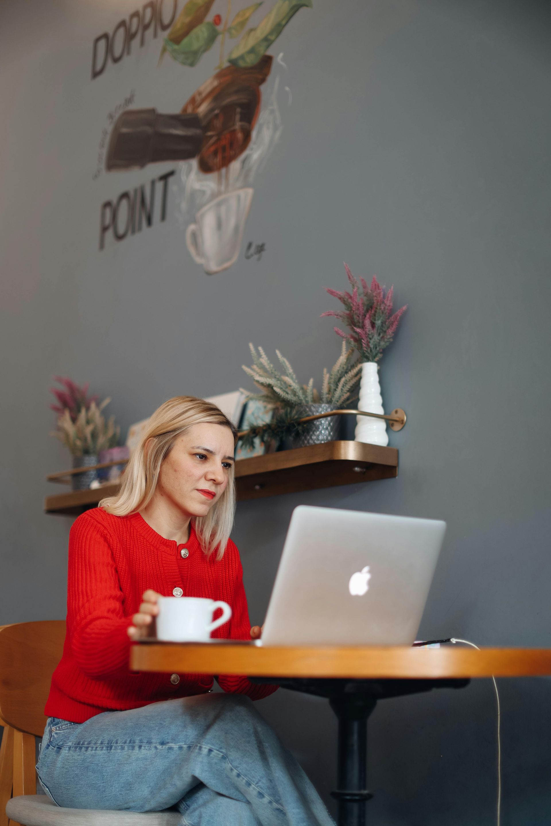 A woman is sitting at a table with a laptop and a cup of coffee.